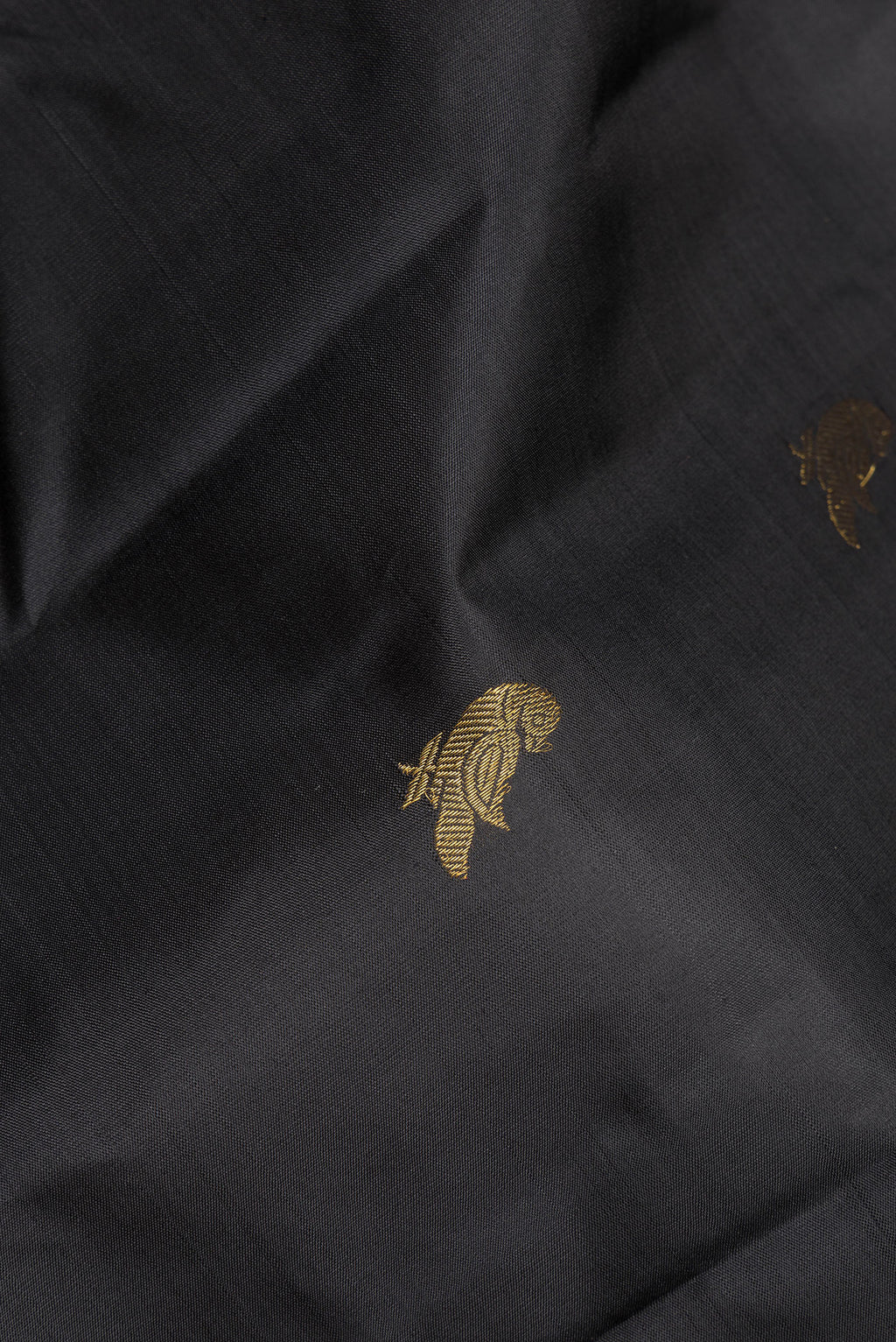 Close up of Pure Silk Black Kanchipuram Saree with Zari Butta on the body and Zari Border.  displaying folds