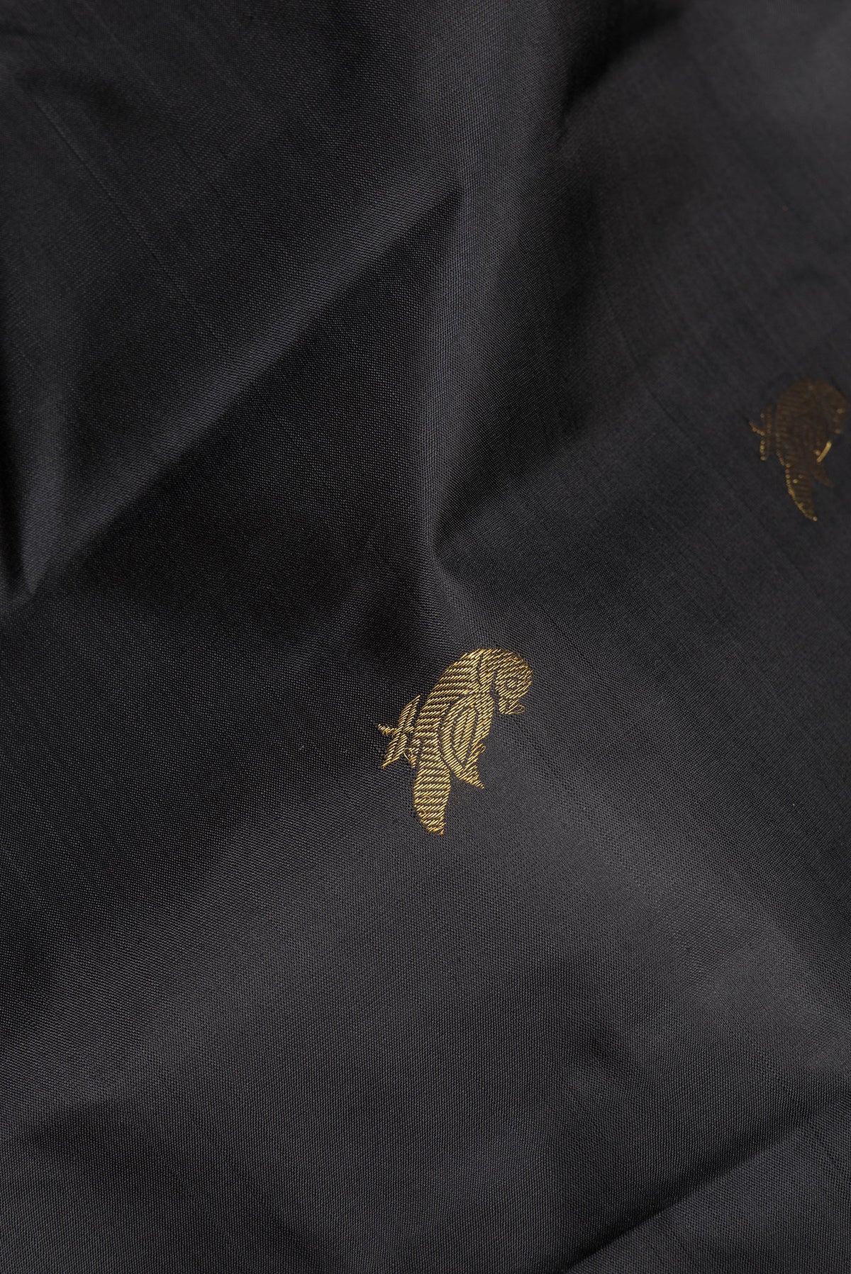 Close up of Pure Silk Black Kanchipuram Saree with Zari Butta on the body and Zari Border.  displaying folds