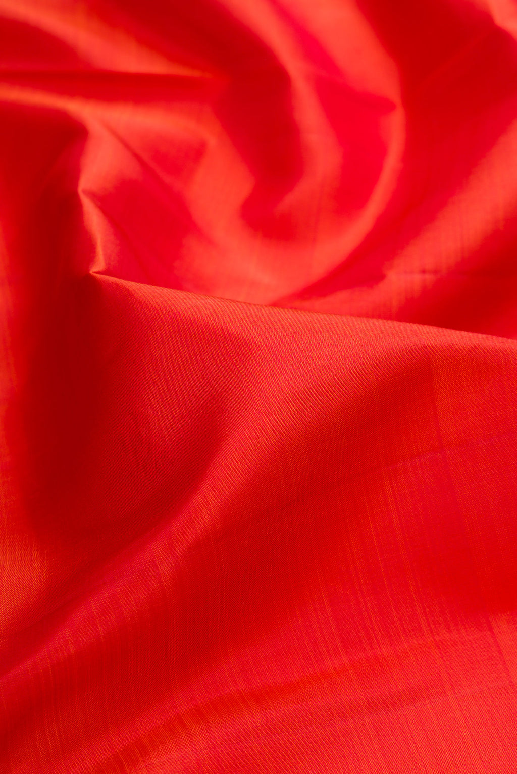 Close up of Pure Silk Brick Orange Kanjivaram Saree with Plain Body and Zari Border.  displaying folds