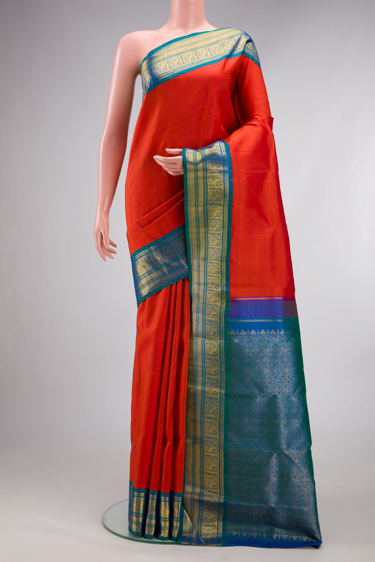 Pure Silk Brick Orange Kanjivaram Saree with Plain Body and Zari Border.  displayed on a mannequin