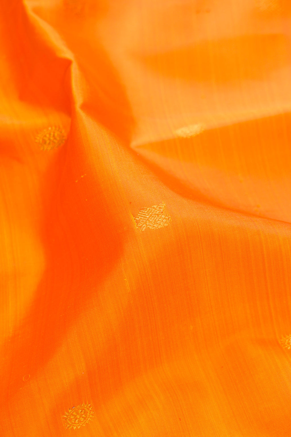 Close up of Pure Silk Orange Dual Tone Kanjivaram Saree with Zari Butta on the body and Zari Border.  displaying folds