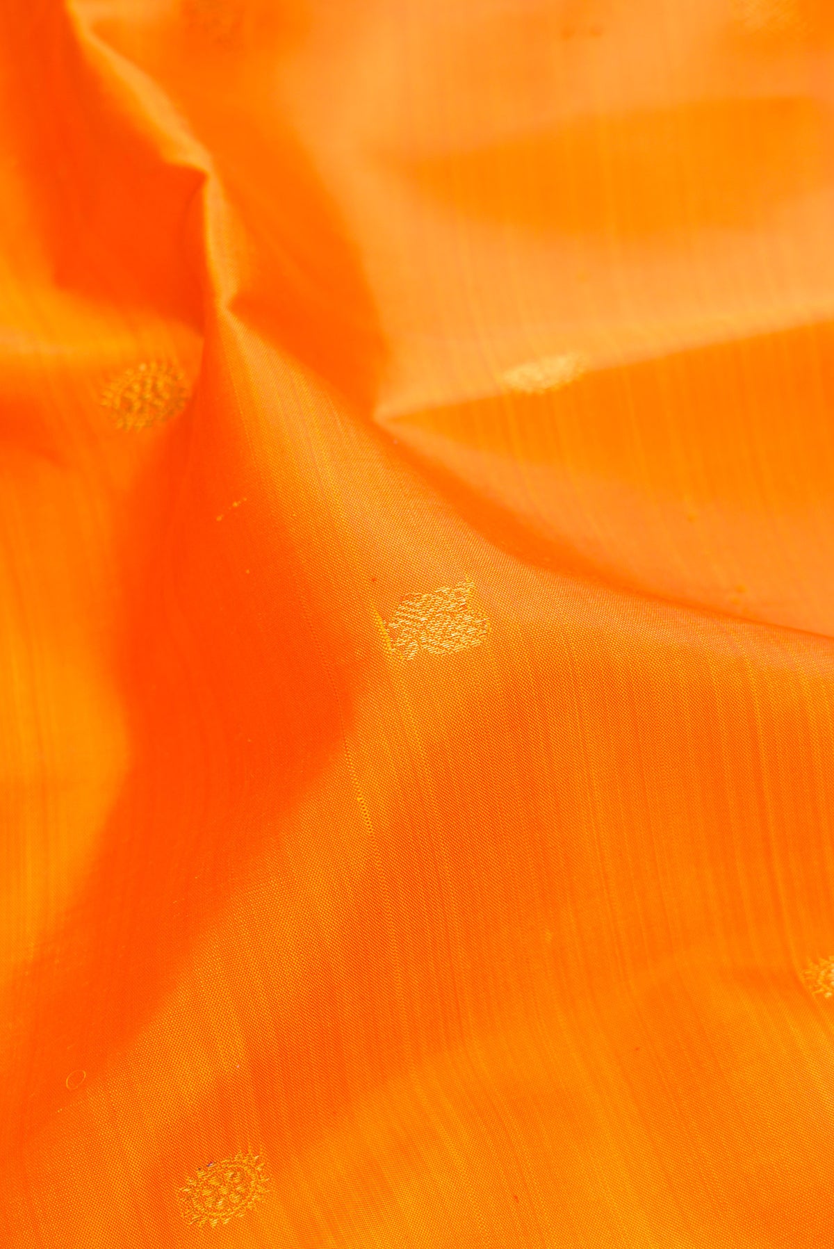 Close up of Pure Silk Orange Dual Tone Kanjivaram Saree with Zari Butta on the body and Zari Border.  displaying folds