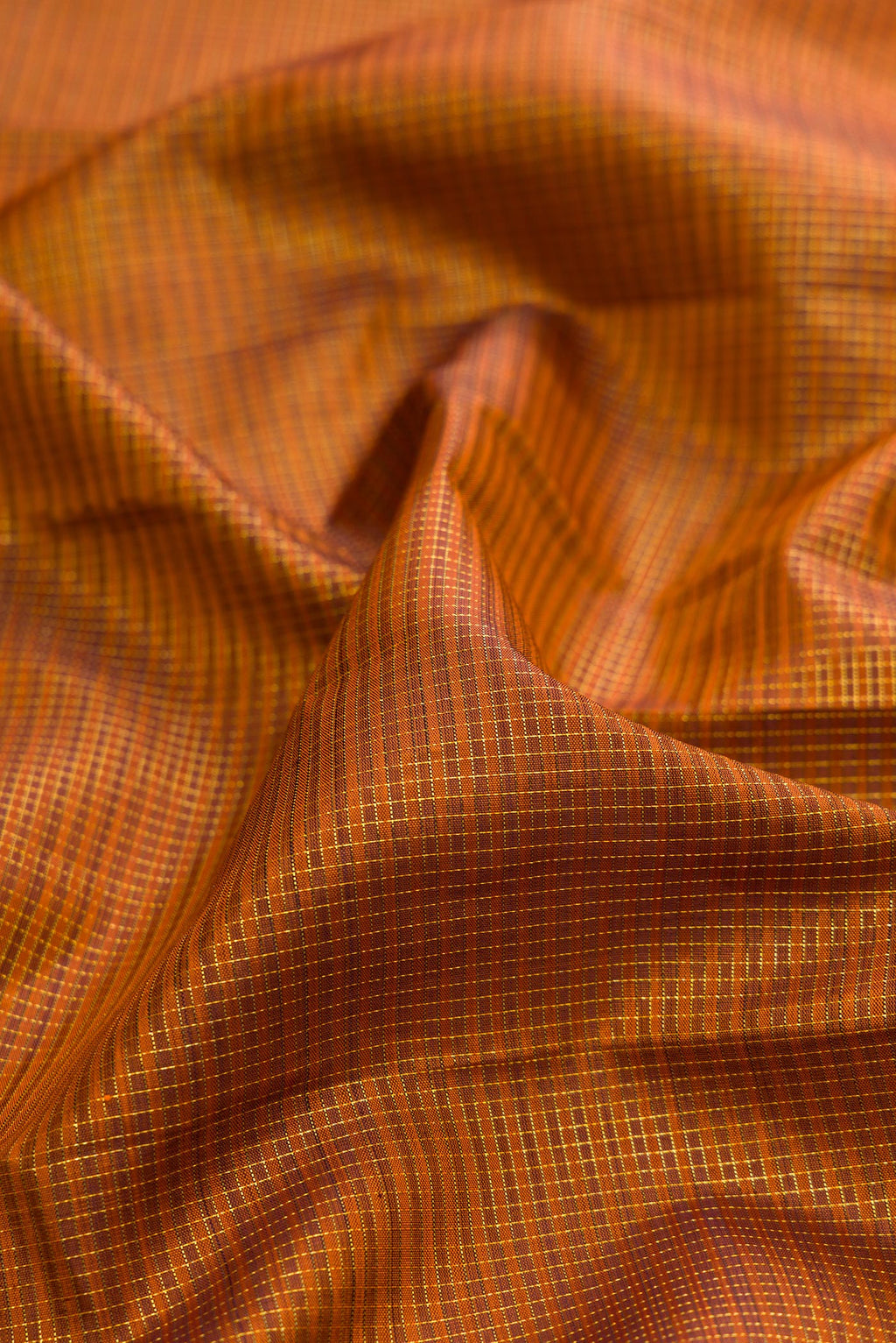 Close up of Pure Silk Brick Orange Kanchipuram Saree with Checked design on the body and Zari Border.  displaying folds