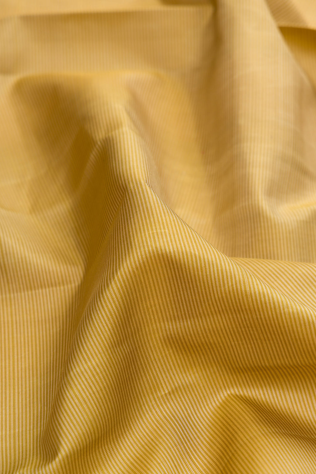 Close up of Pure Silk Gold Kanjivaram Saree with Stripes on the body and Checks Border.  displaying folds