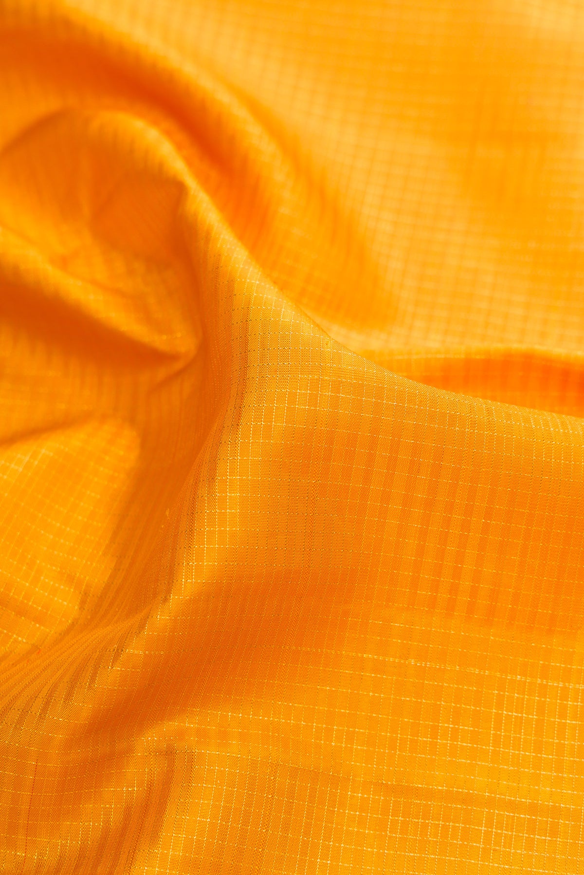 Close up of Pure Silk Mustard Kanjivaram Saree with Checked design on the body and Zari Border.  displaying folds