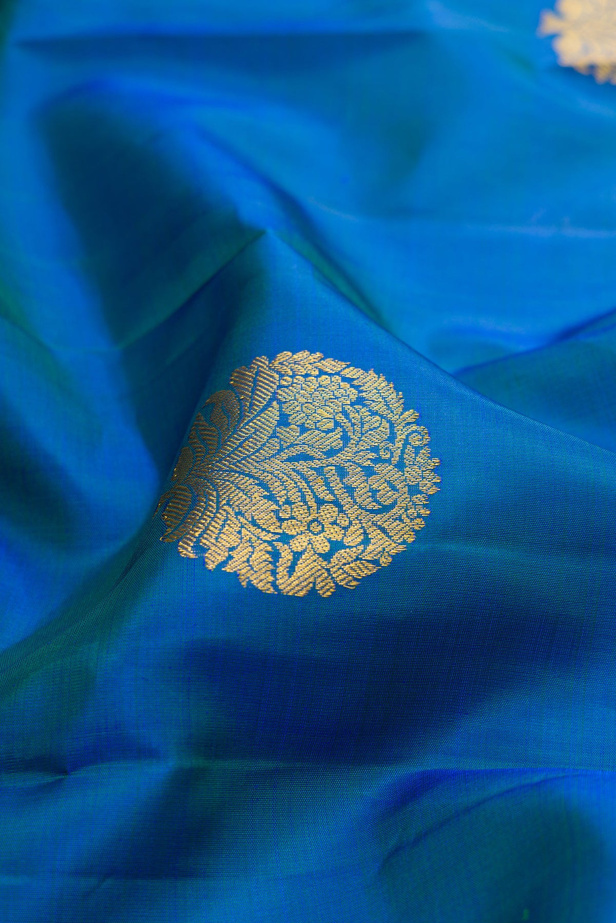 Close up of Pure Silk Peacock Blue Kanjivaram Saree with Zari Butta on the body and Zari Border.  displaying folds