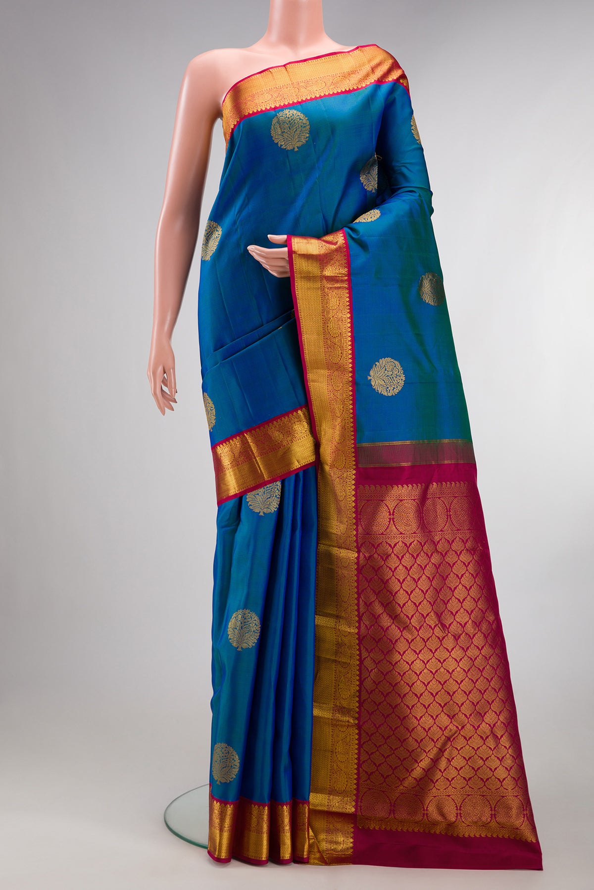 Pure Silk Peacock Blue Kanjivaram Saree with Zari Butta on the body and Zari Border.  displayed on a mannequin