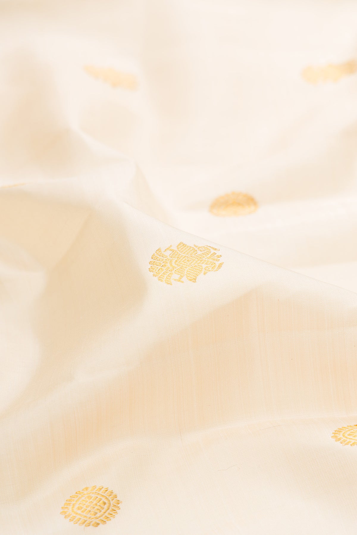 Close up of Pure Silk Cream Kanjivaram Saree with Zari Butta on the body and Fancy Border.  displaying folds