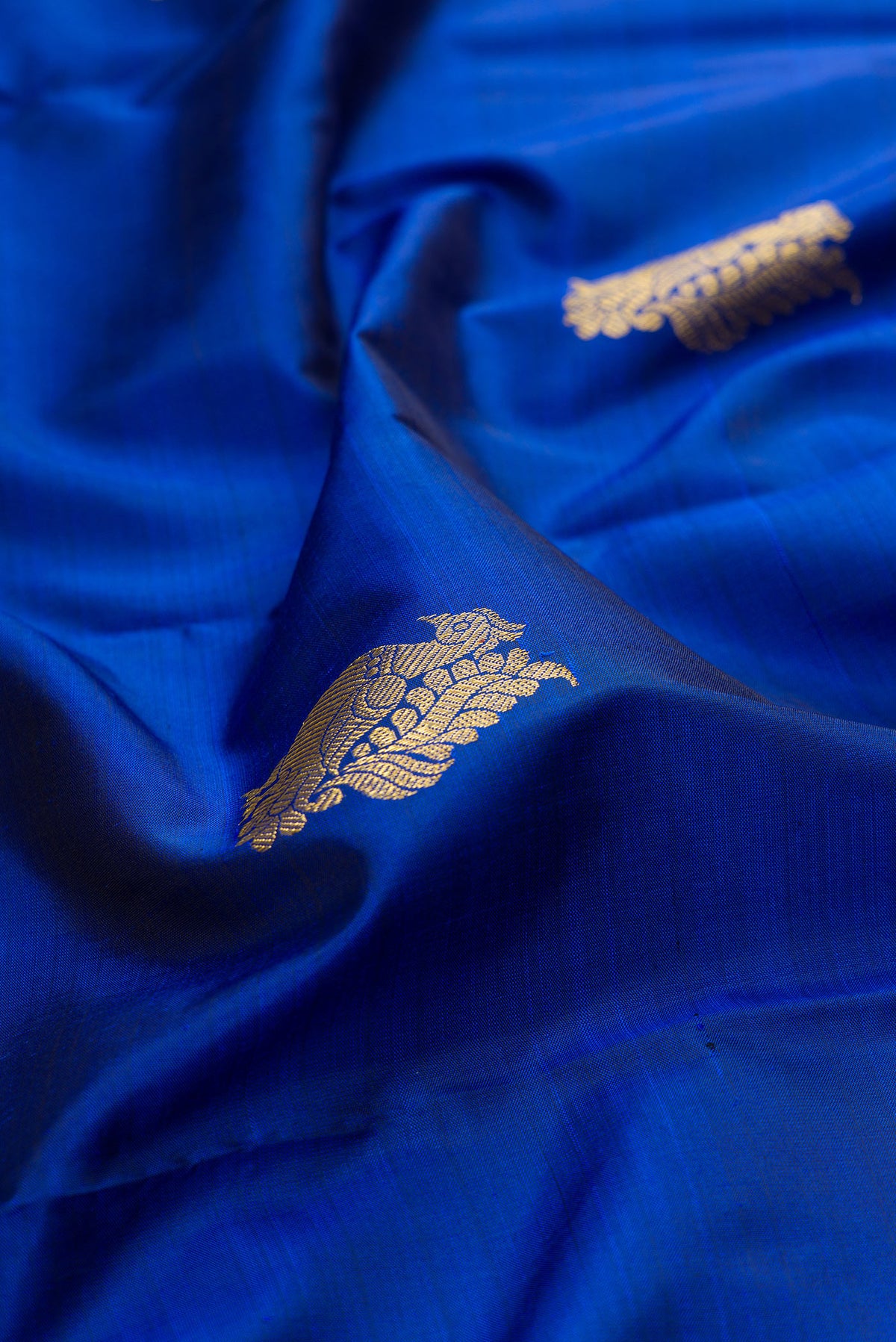 Close up of Pure Silk Royal Blue Kanjivaram Saree with Zari Butta on the body and Zari Border.  displaying folds