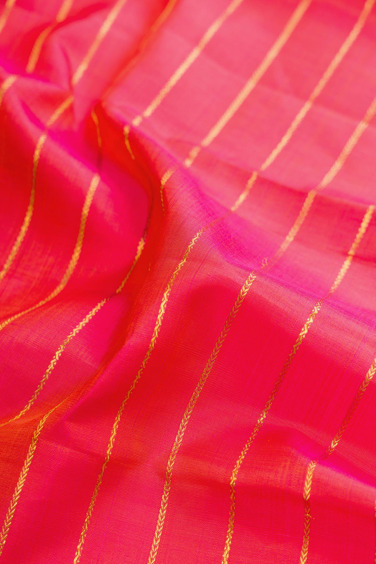 Close up of Pure Silk Coral Dual Tone Kanjivaram Saree with Veldhari on the body and Ganga Jamuna Border.  displaying folds