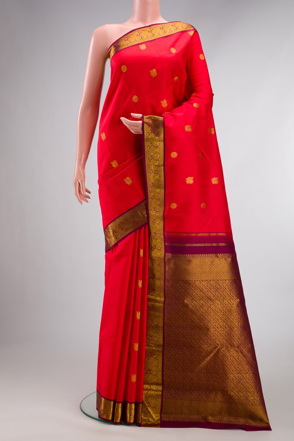 Pure Silk Red Kanjivaram Saree with Zari Butta on the body and Zari Border.  displayed on a mannequin