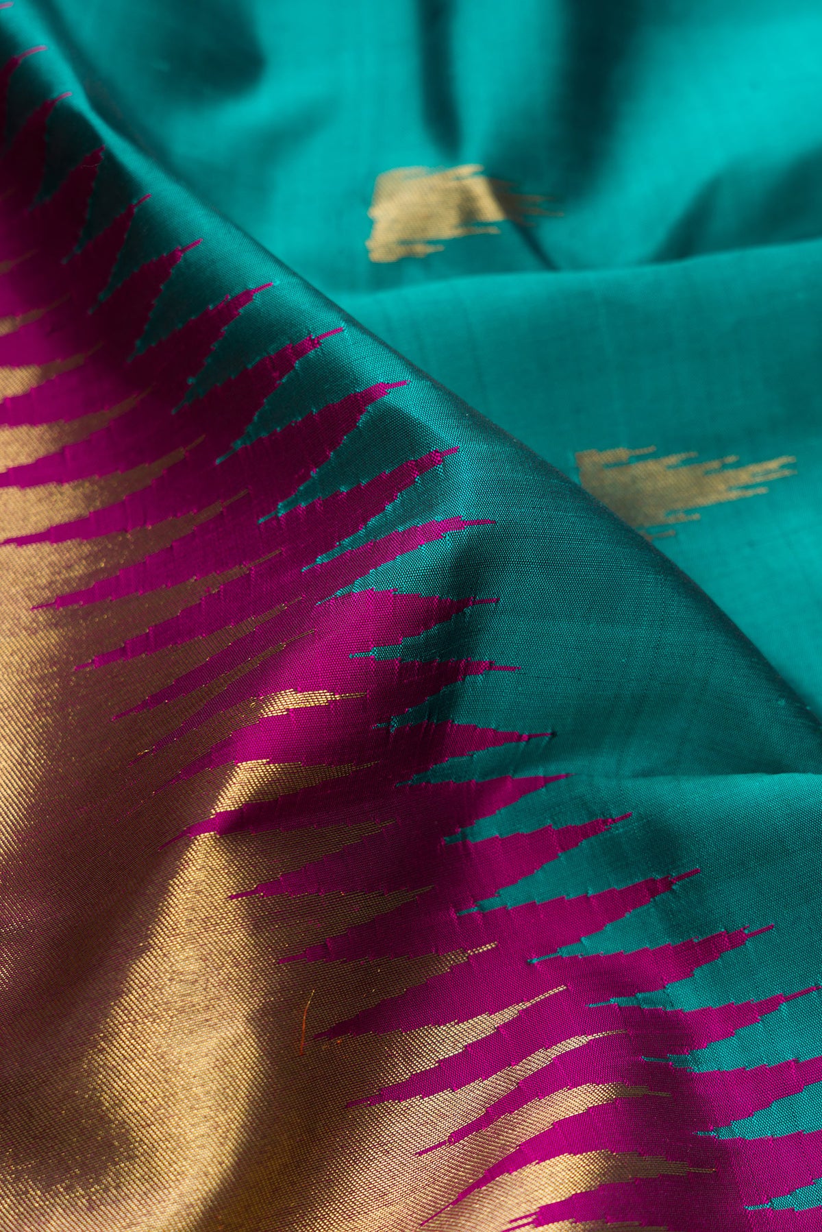Close up of Pure Silk Pure Zari Teal Kanjivaram Saree with Zari Butta on the body and Rising Temple Border.  displaying folds