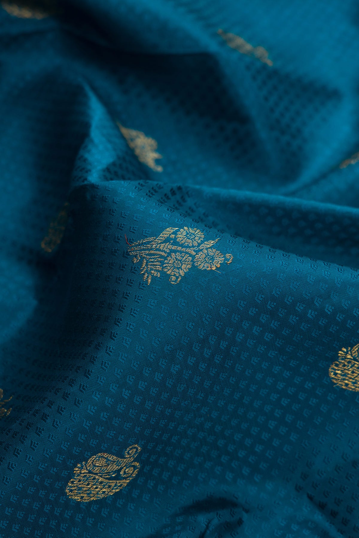 Close up of Pure Silk Pure Zari Peacock Blue Dual Tone Kanchipuram Saree with Jacquard With Zari Butta on the body and Zari Border.  displaying folds
