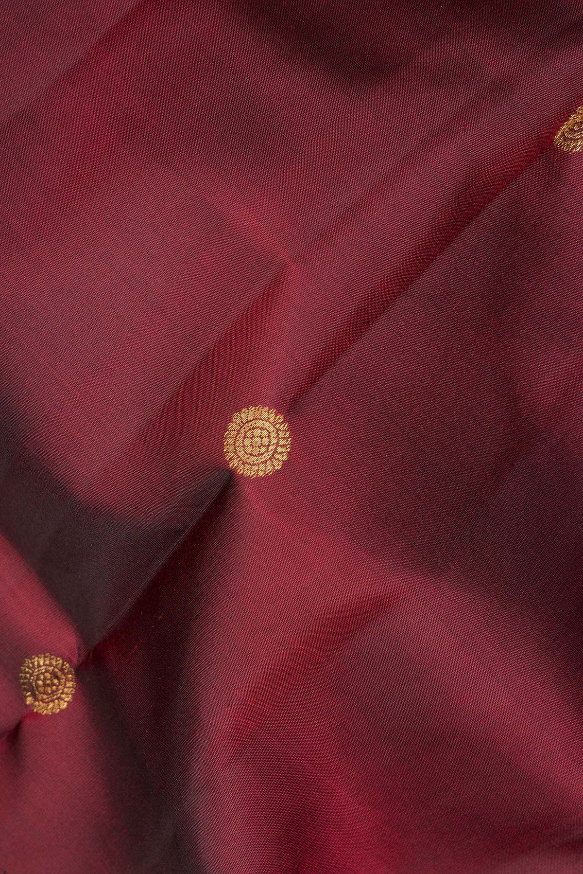 Close up of Pure Silk Maroon Kanjivaram Saree with Zari Butta on the body and Zari Border.  displaying folds