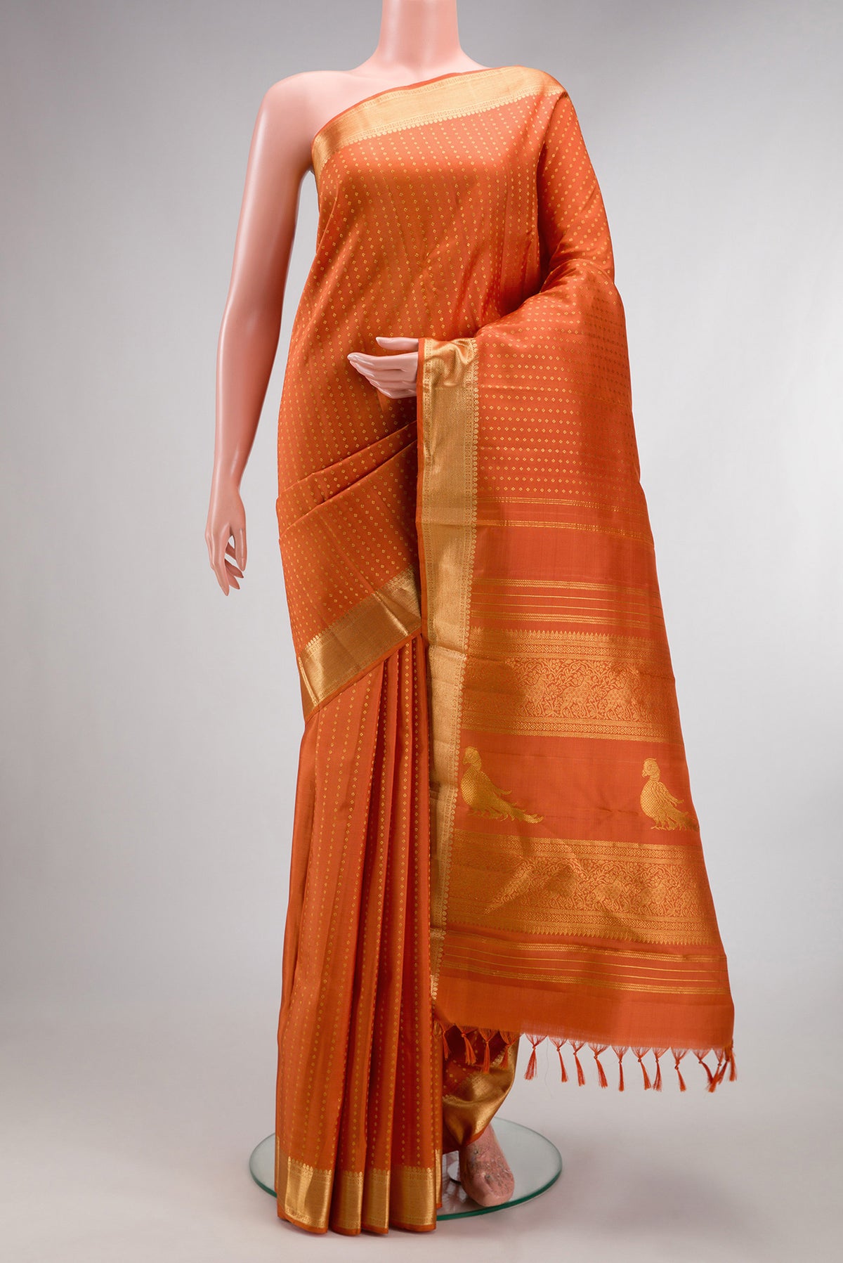 Pure Silk Brick Orange Kanchipuram Saree with Zari Butta on the body and Zari Border.  displayed on a mannequin