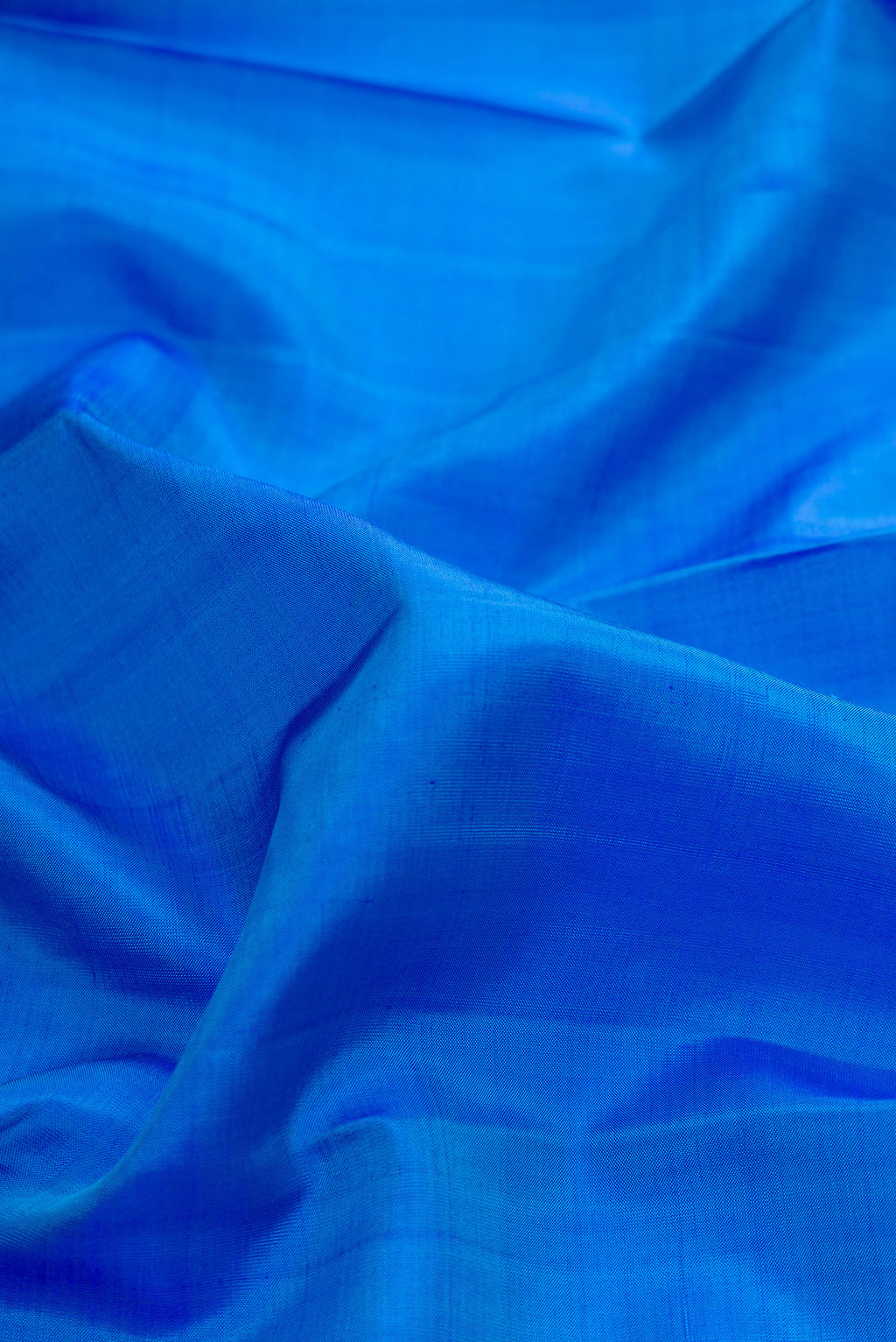 Close up of Pure Silk Royal Blue Kanchipuram Saree with Plain Body and Zari Border.  displaying folds