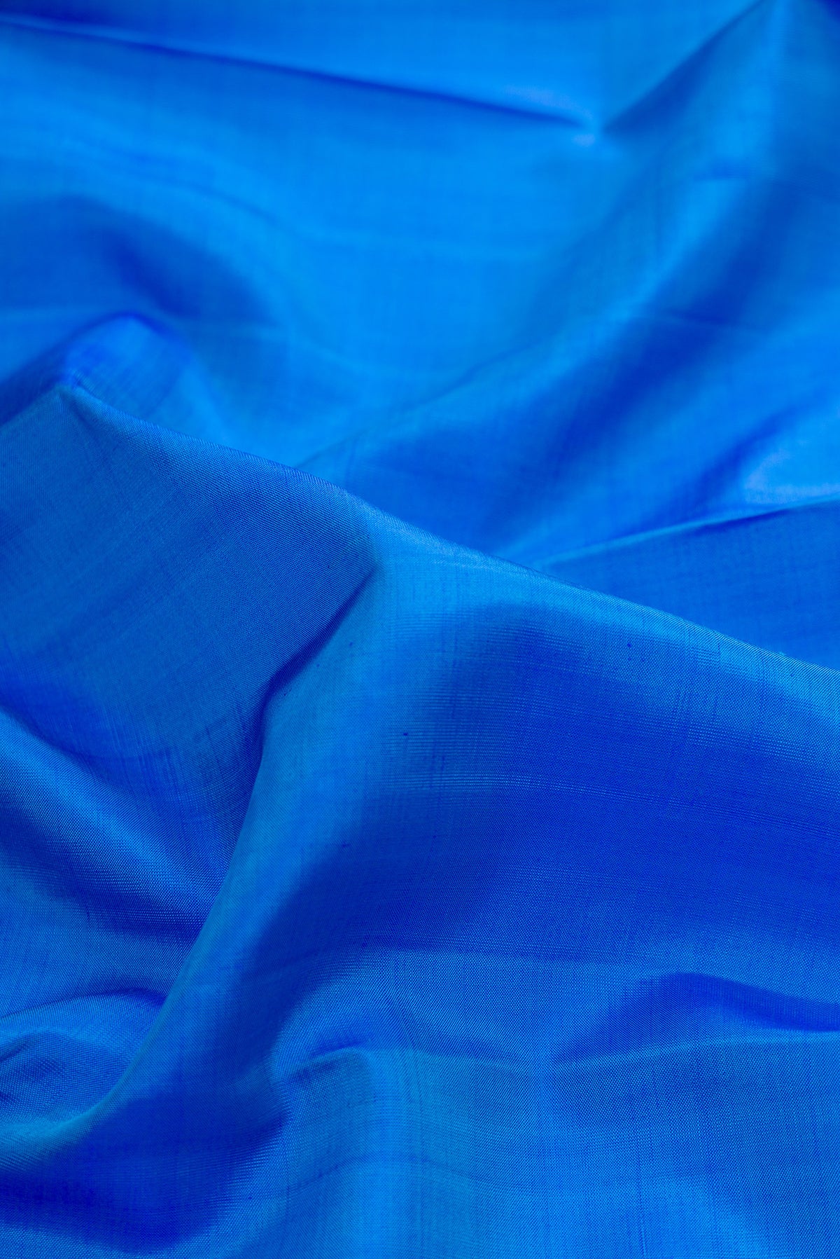 Close up of Pure Silk Royal Blue Kanchipuram Saree with Plain Body and Zari Border.  displaying folds