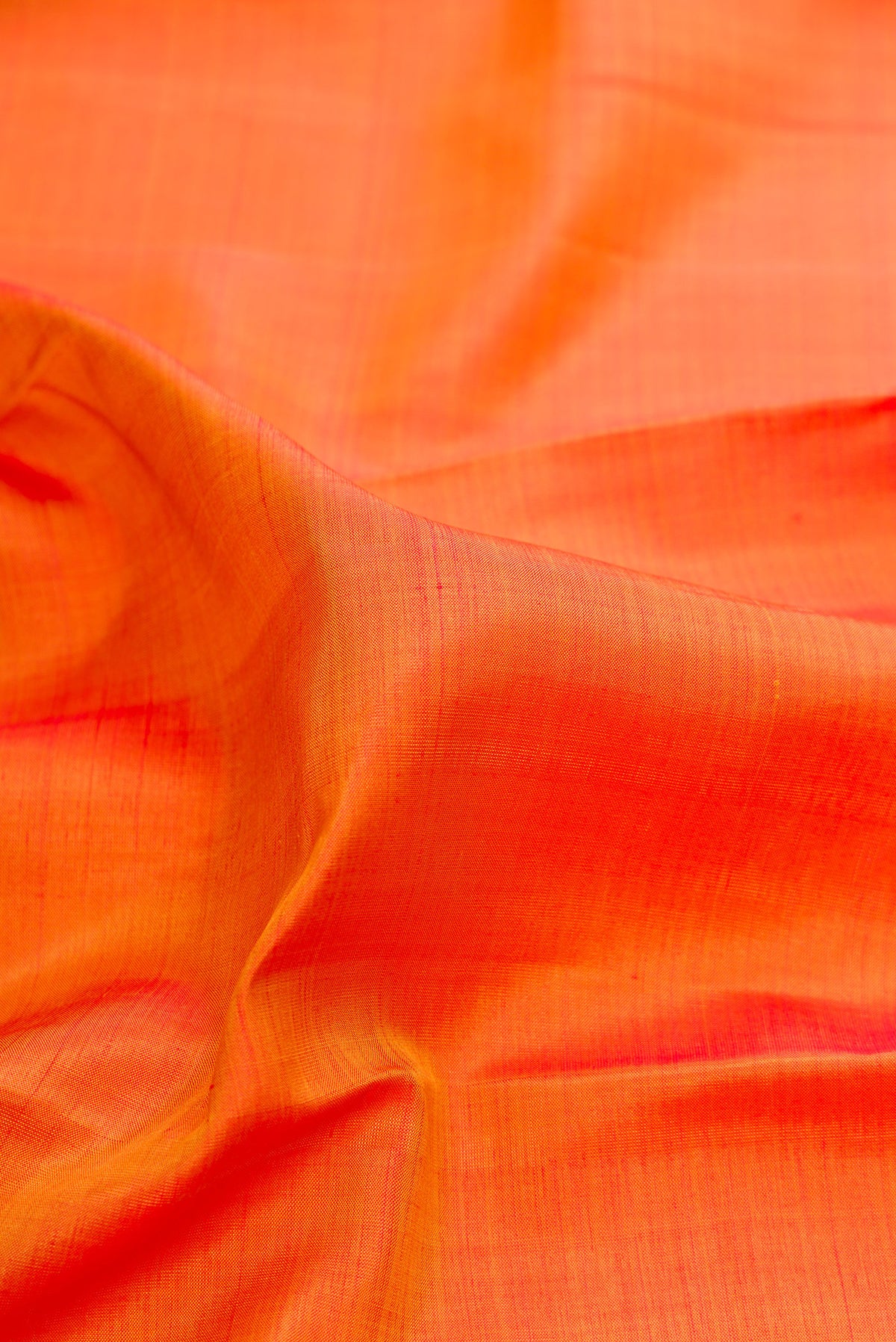 Close up of Pure Silk Orange Dual Tone Kanchipuram Saree with Plain Body and Zari Border.  displaying folds