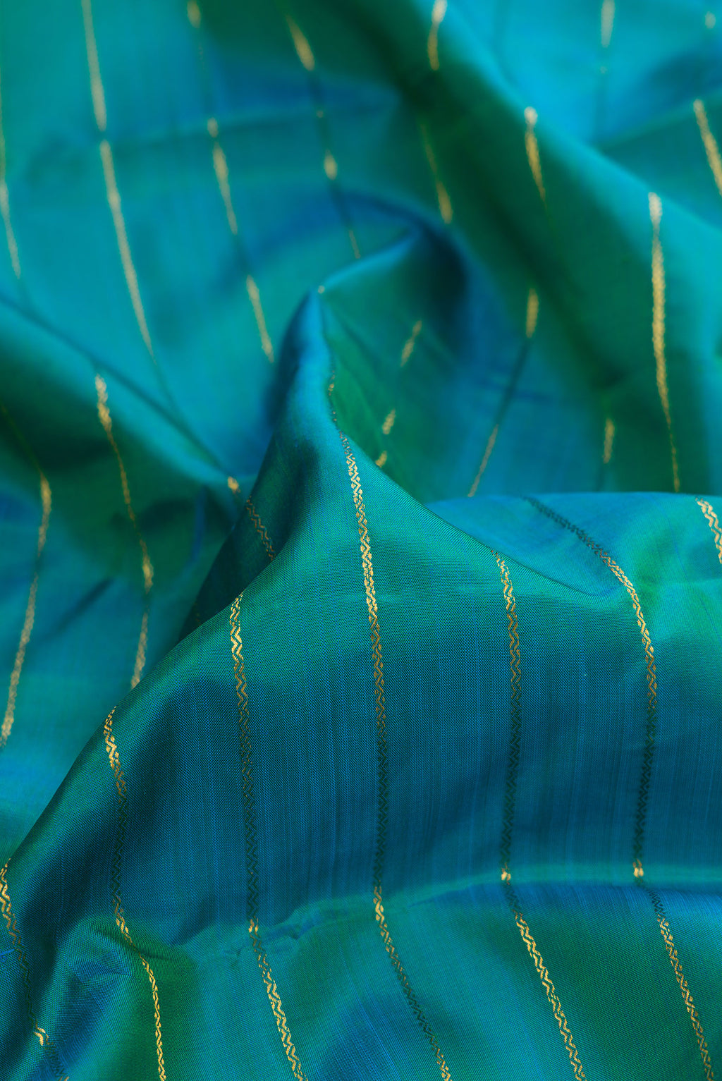 Close up of Pure Silk Peacock Blue Dual Tone Kanchipuram Saree with Veldhari on the body and Zari Border.  displaying folds