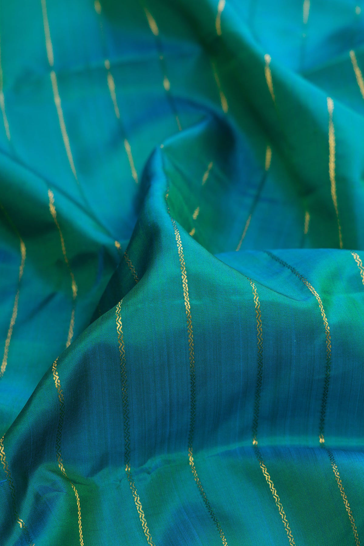 Close up of Pure Silk Peacock Blue Dual Tone Kanchipuram Saree with Veldhari on the body and Zari Border.  displaying folds