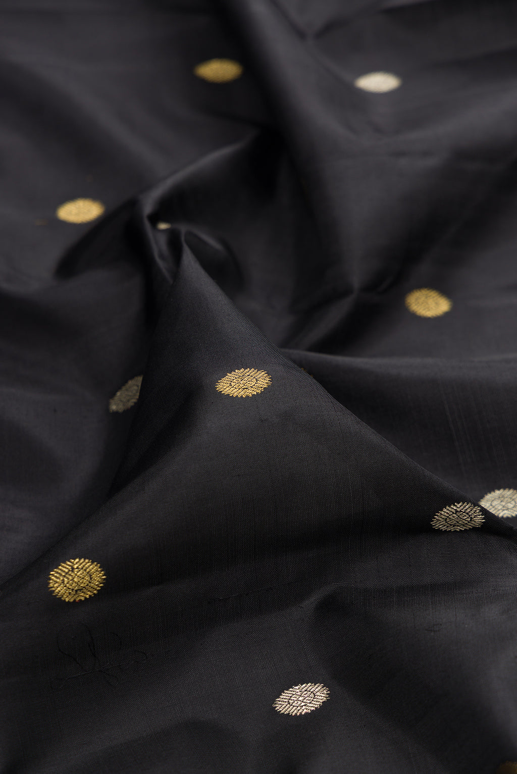 Close up of Pure Silk Black Kanjivaram Saree with Zari Butta on the body and Fancy Border.  displaying folds
