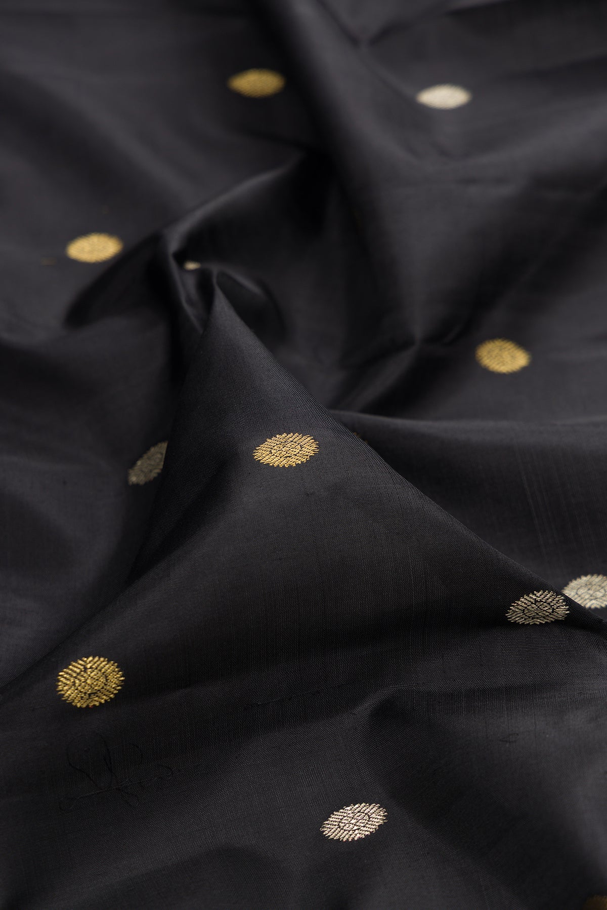 Close up of Pure Silk Black Kanjivaram Saree with Zari Butta on the body and Fancy Border.  displaying folds