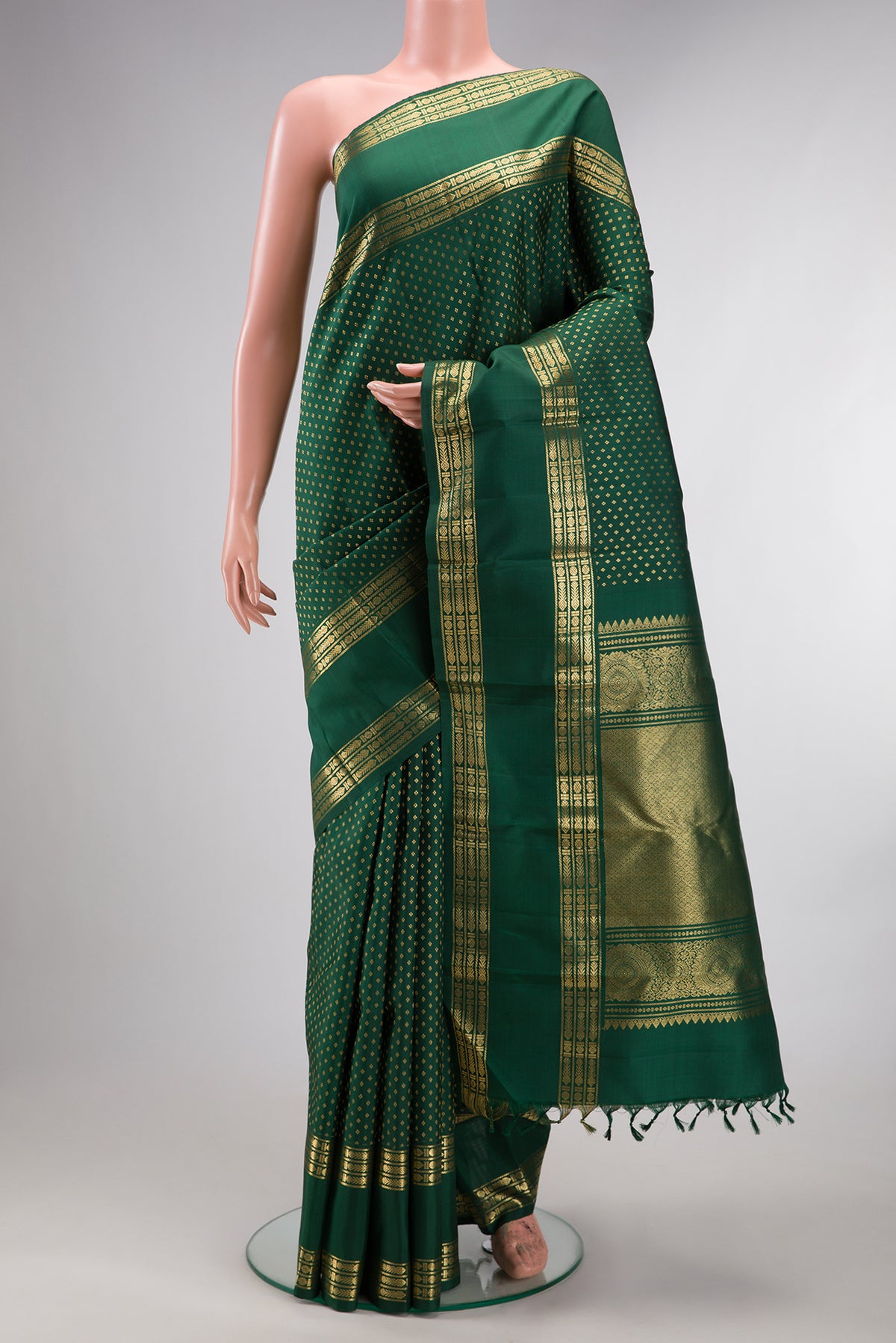 Pure Silk Green Kanjivaram Saree with Zari Butta on the body and Zari Border.  displayed on a mannequin