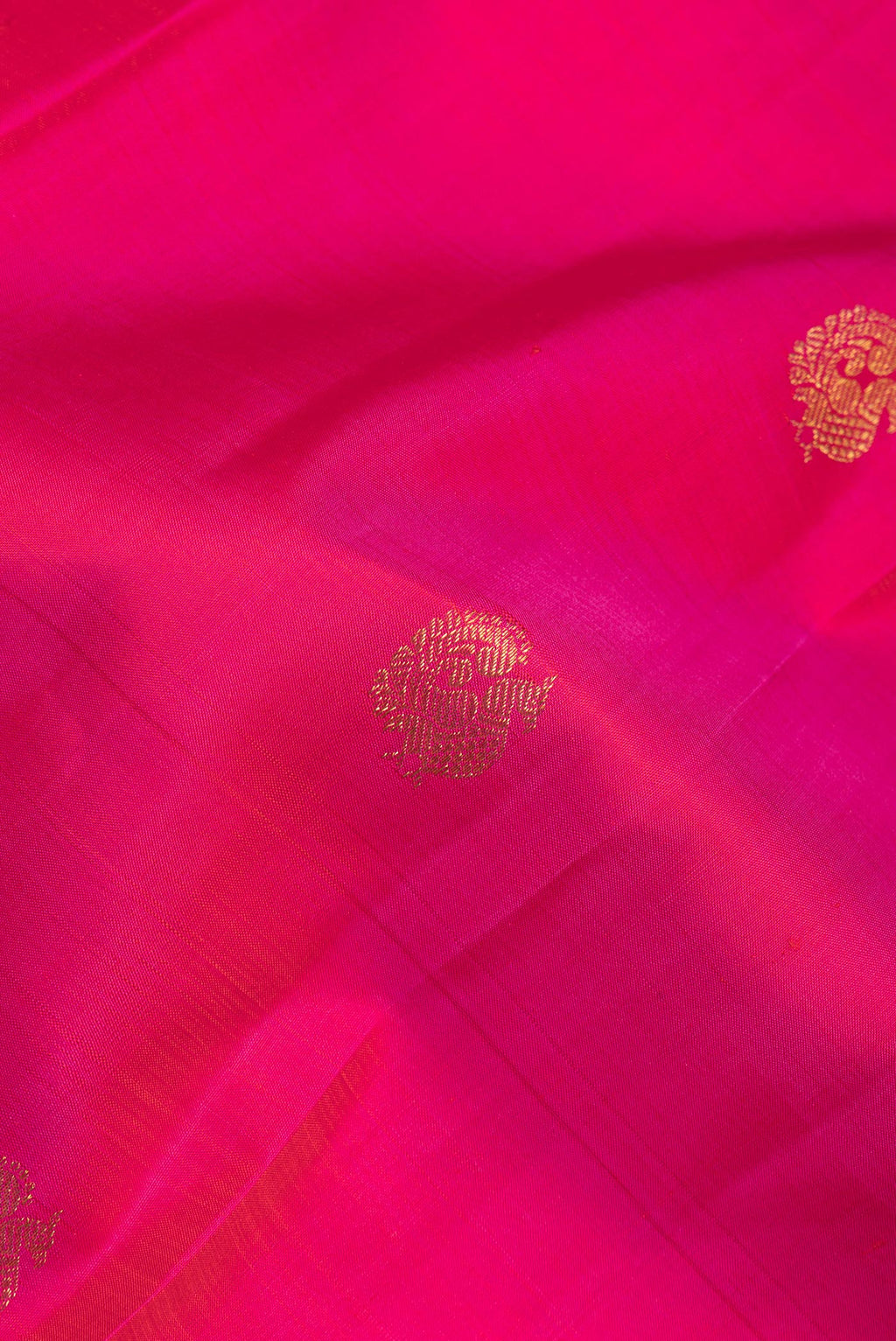 Close up of Pure Silk Dark Pink Kanjivaram Saree with Zari Butta on the body and Zari Border.  displaying folds