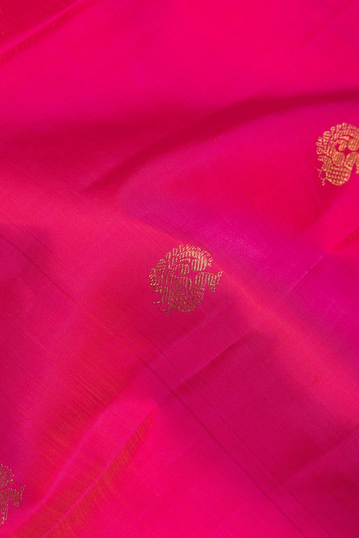 Close up of Pure Silk Dark Pink Kanjivaram Saree with Zari Butta on the body and Zari Border.  displaying folds