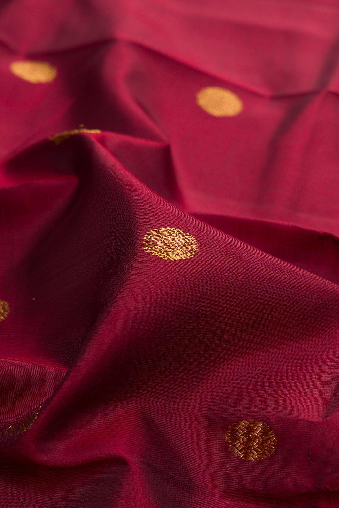 Close up of Pure Silk Maroon Kanjivaram Saree with Zari Butta on the body and Temple Border.  displaying folds