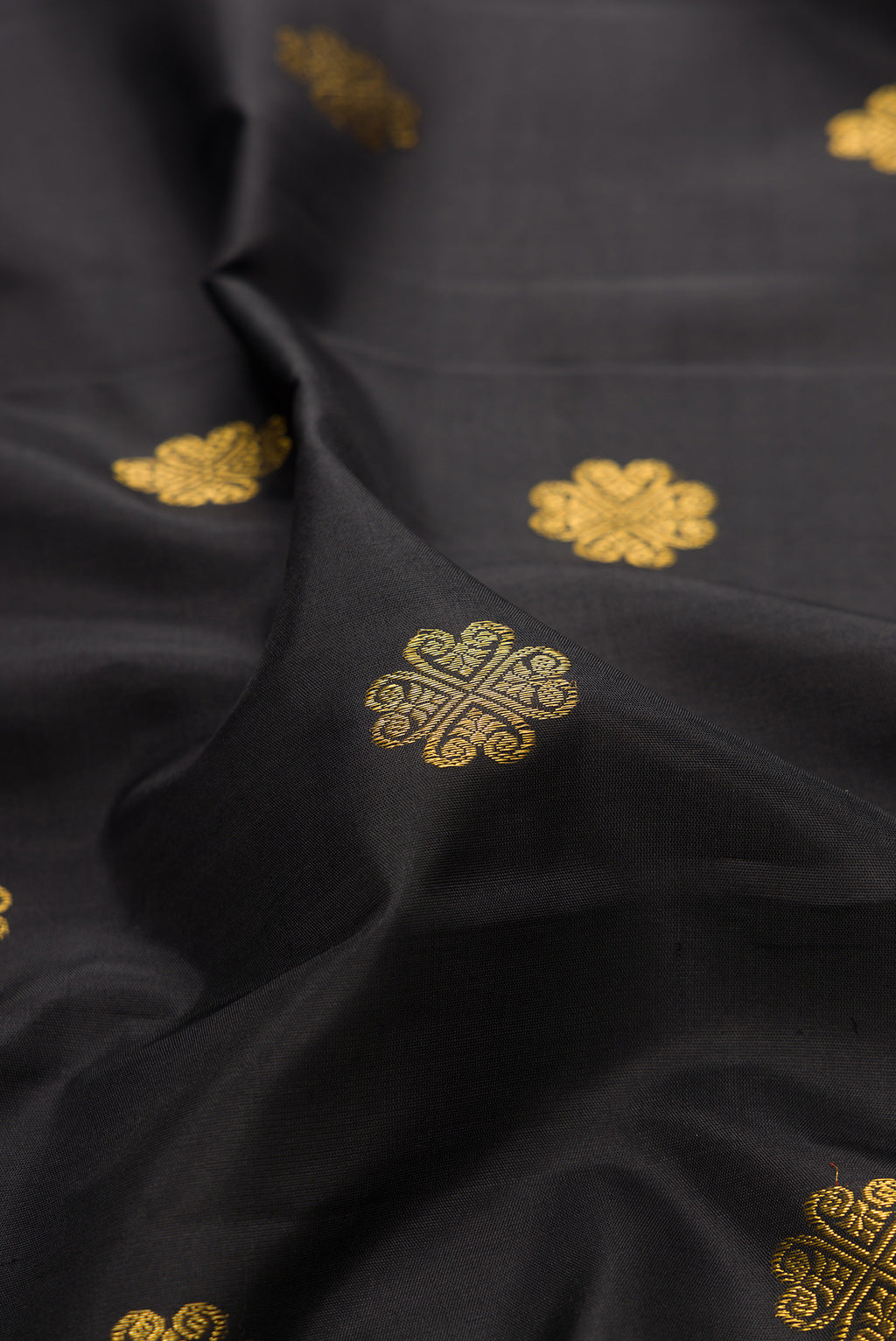 Close up of Pure Silk Pure Zari Black Dual Tone Kanjivaram Saree with Zari Butta on the body and Zari Border.  displaying folds