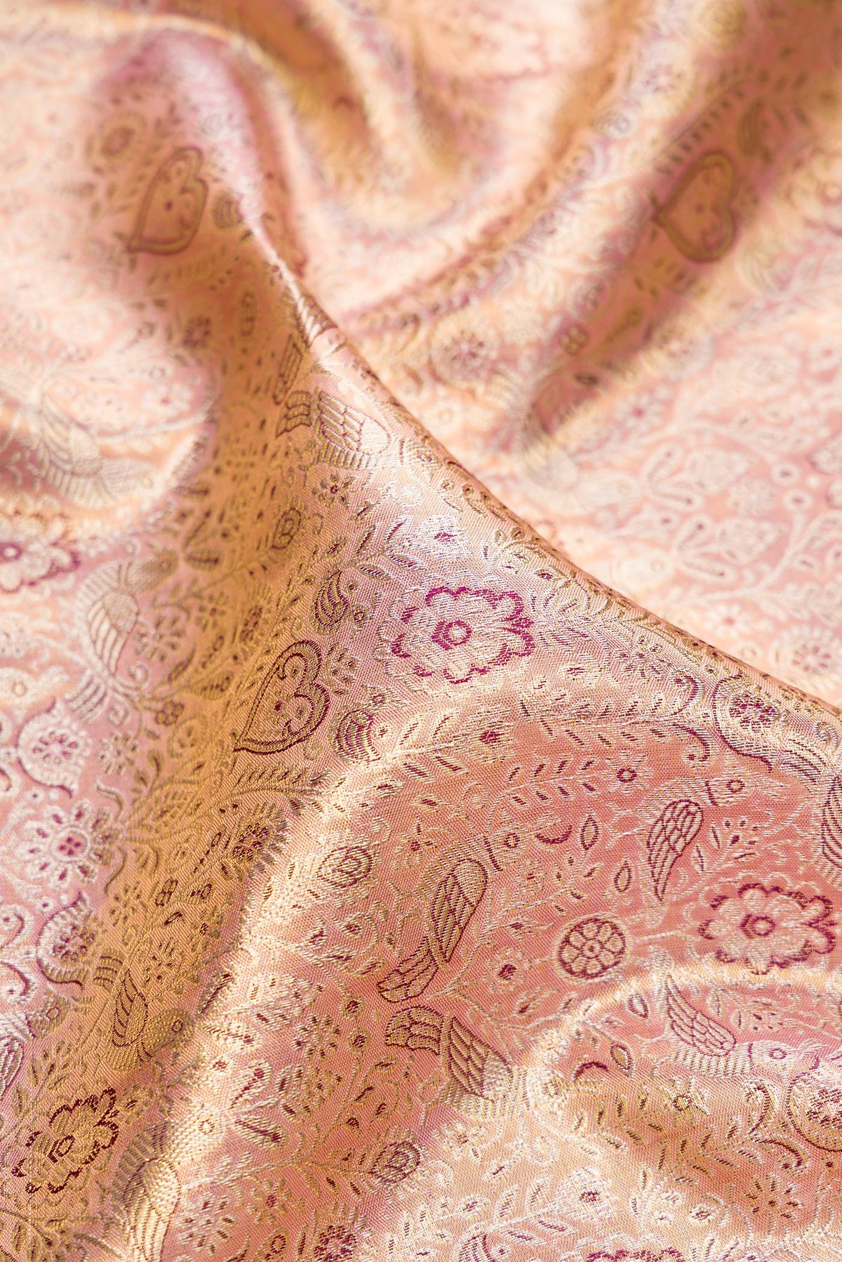 Close up of Rose Gold Dual Tone Kanjivaram Tissue Saree with Zari Brocade on the body and Zari Border.  displaying folds