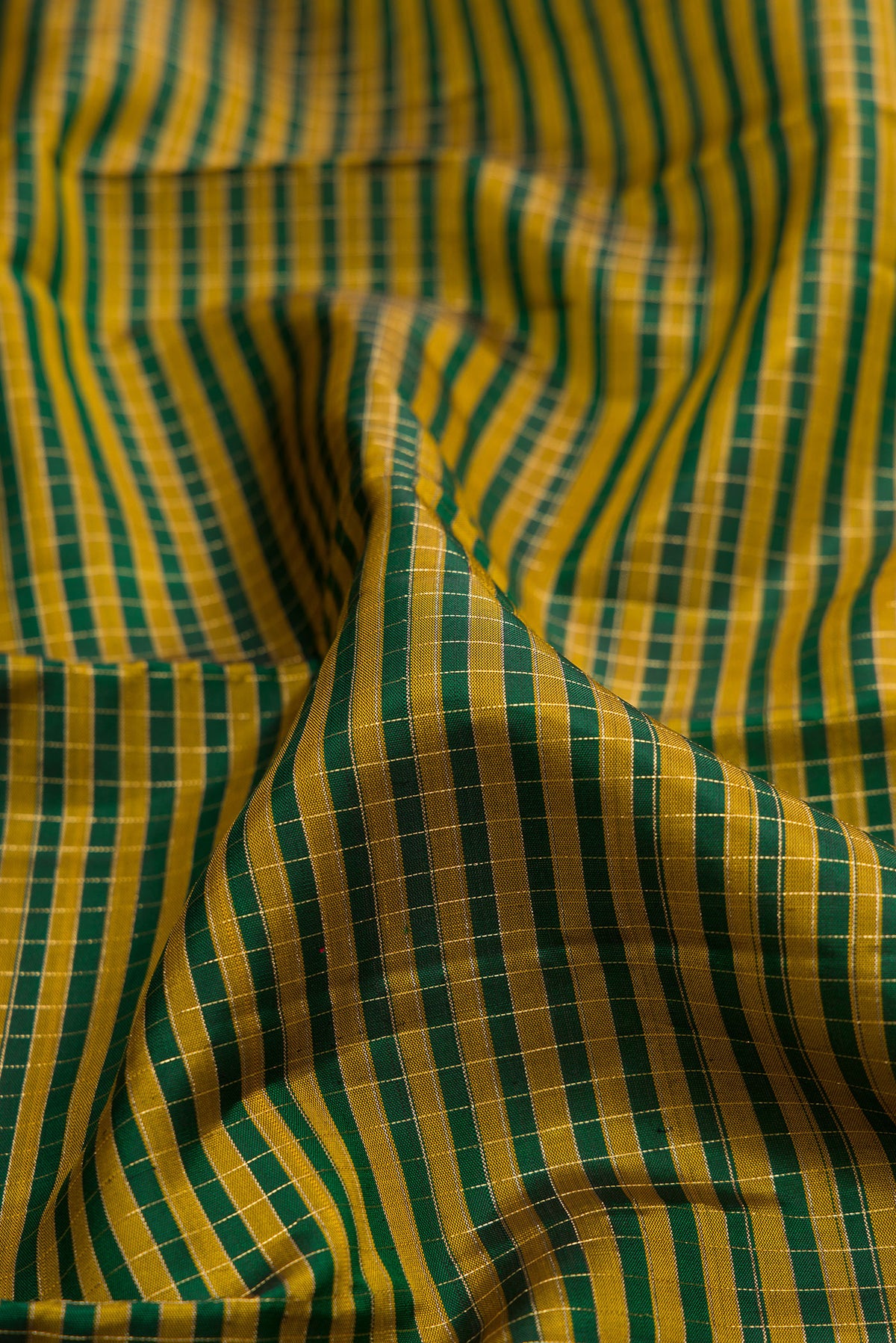 Close up of Pure Silk Bottle Green Kanjivaram Saree with Checked design on the body and Zari Border.  displaying folds