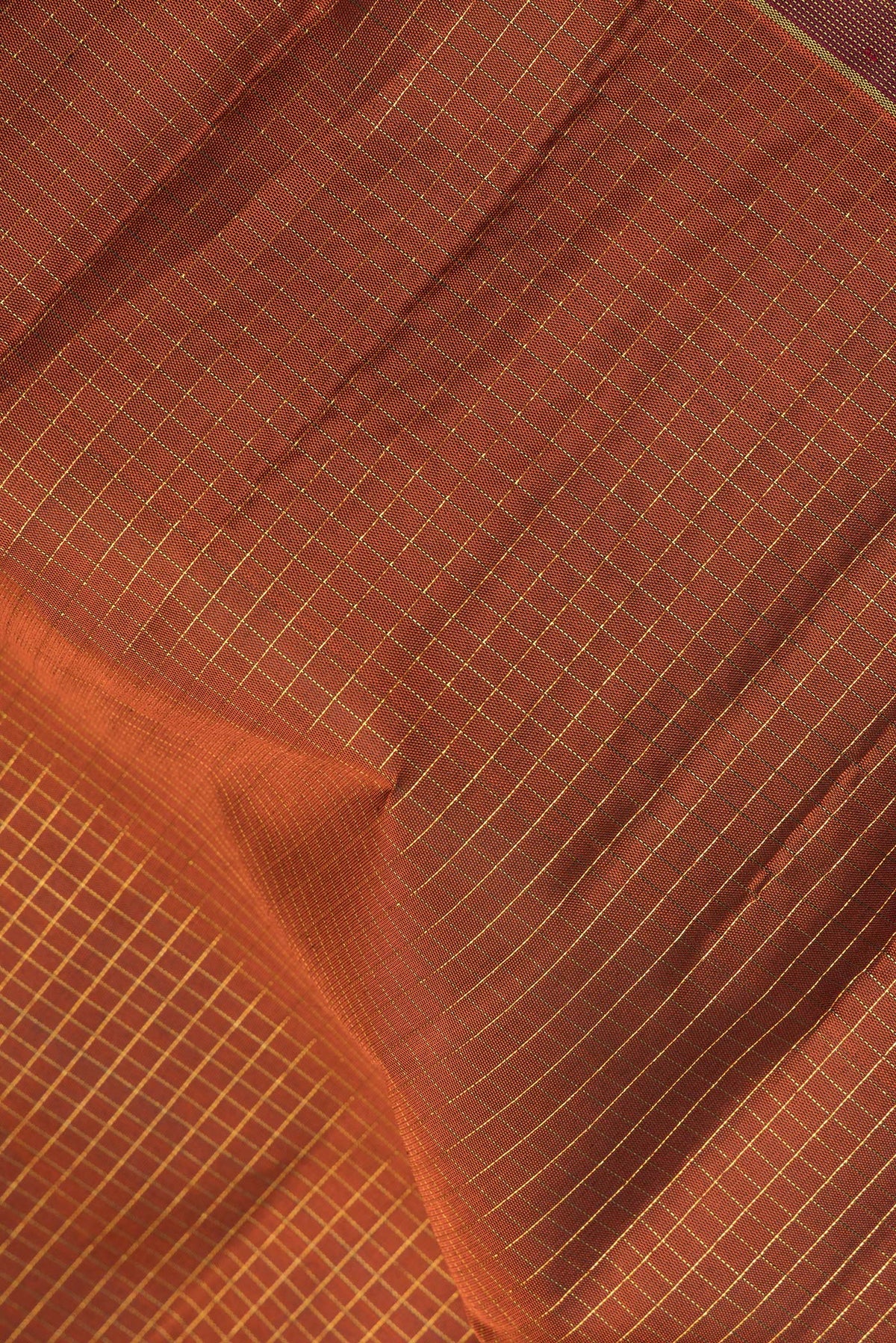 Close up of Pure Silk Rust Kanjivaram Saree with Checked design on the body and Ganga Jamuna Border.  displaying folds