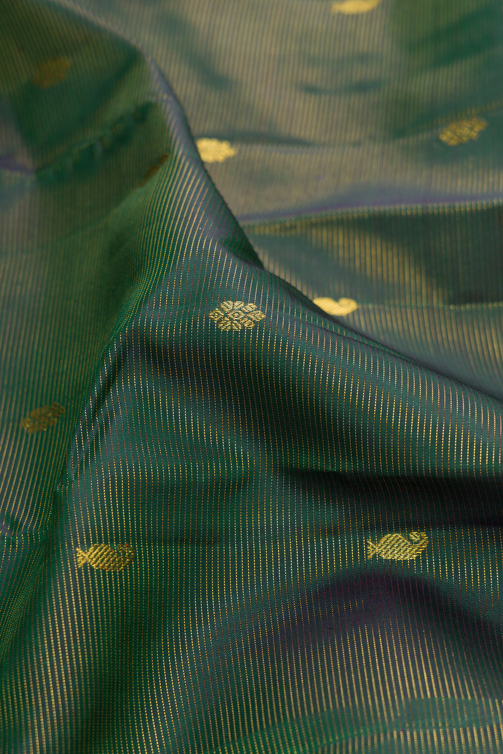 Close up of Pure Silk Bottle Green Kanjivaram Saree with Zari Butta on the body and Zari Border.  displaying folds