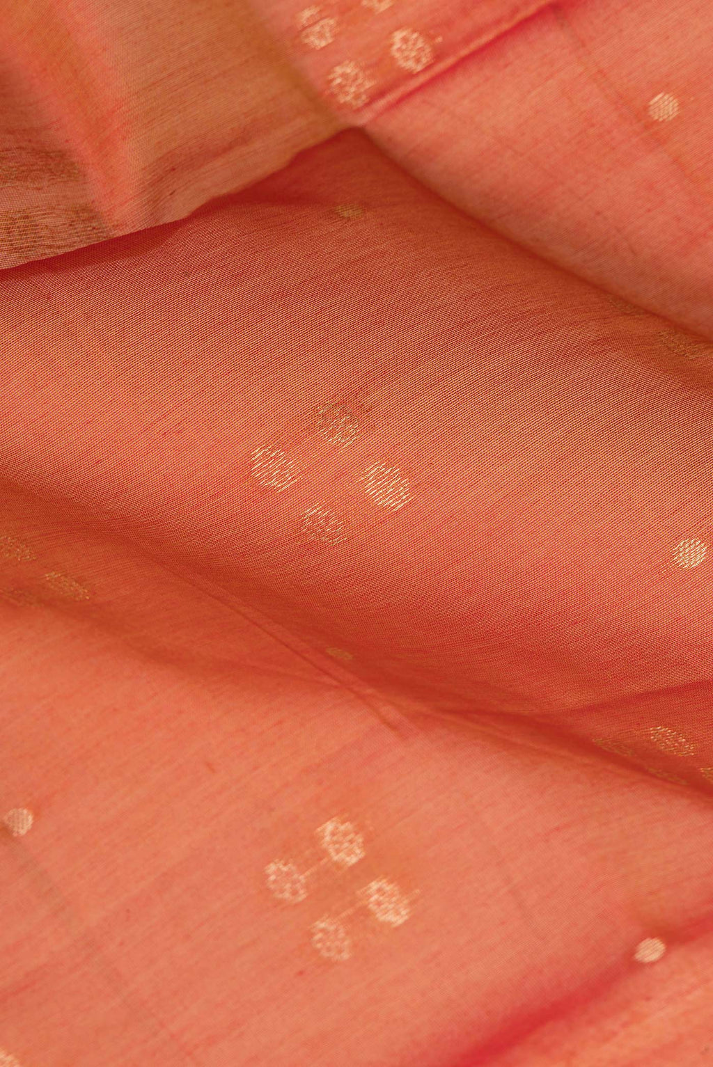 Close up of Rust Silk Cotton Saree with Zari Butta on the body and Zari Border.  displaying folds
