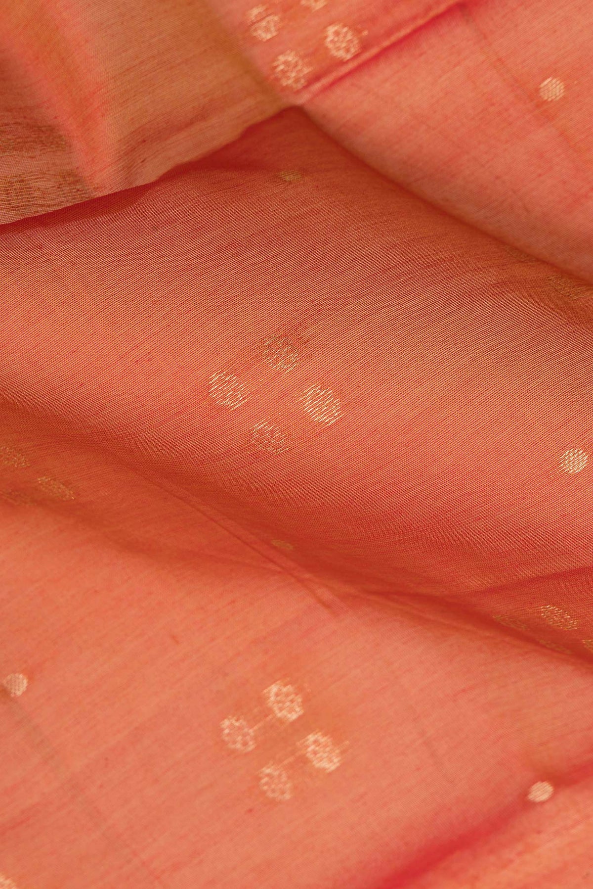 Close up of Rust Silk Cotton Saree with Zari Butta on the body and Zari Border.  displaying folds