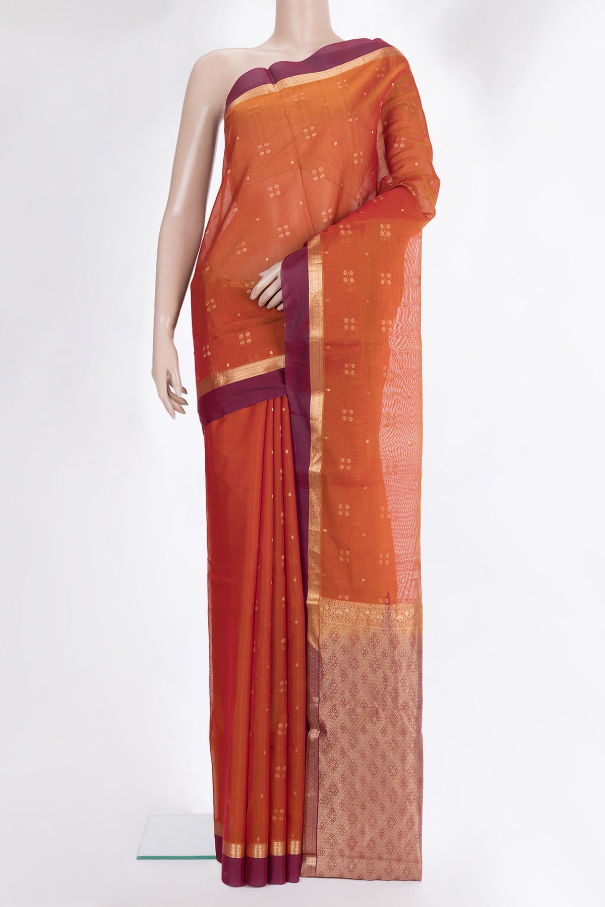 Rust Silk Cotton Saree with Zari Butta on the body and Zari Border.  displayed on a mannequin