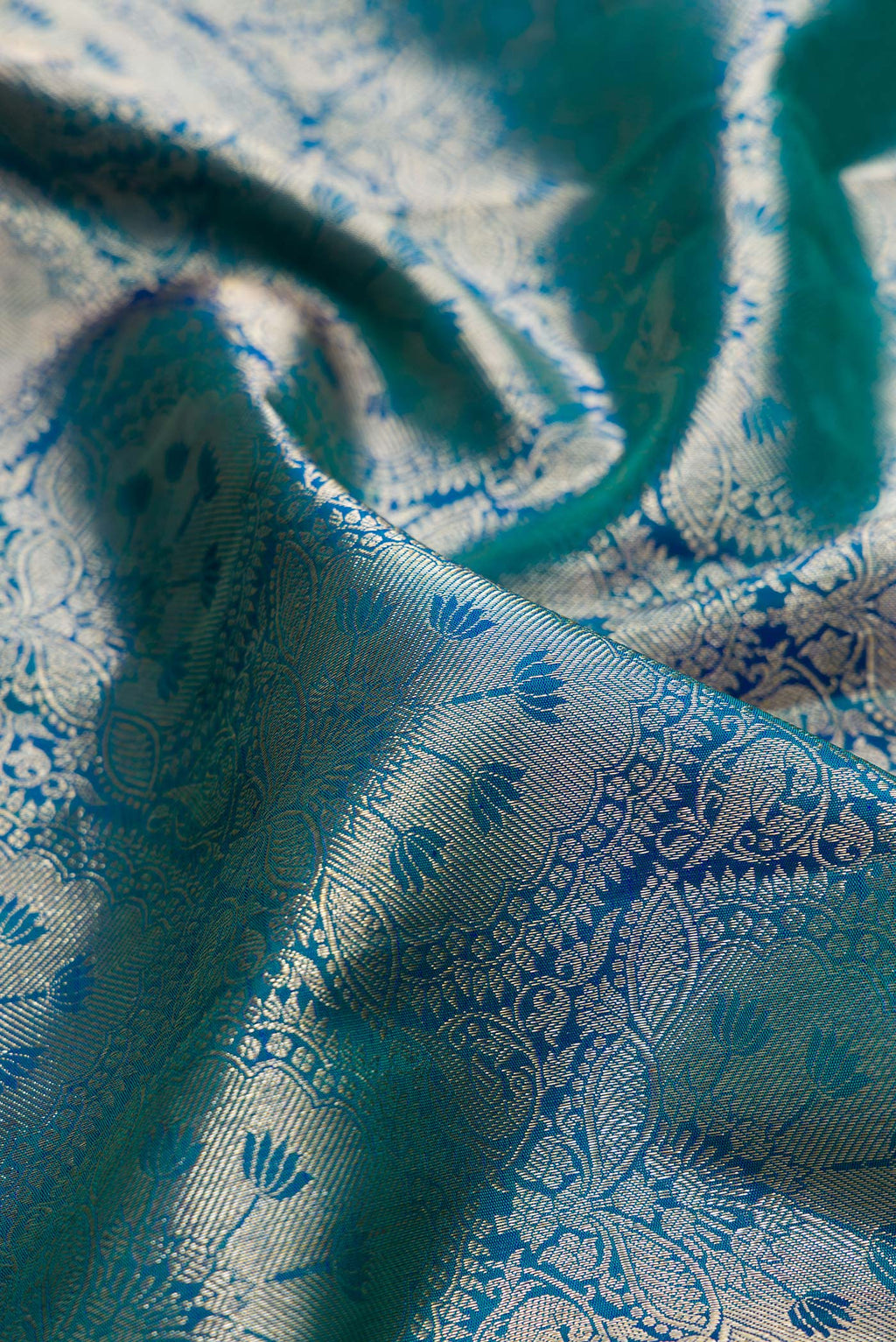 Close up of Pure Silk Peacock Blue Dual Tone Kanchipuram Saree with Zari Brocade on the body and Zari Border.  displaying folds