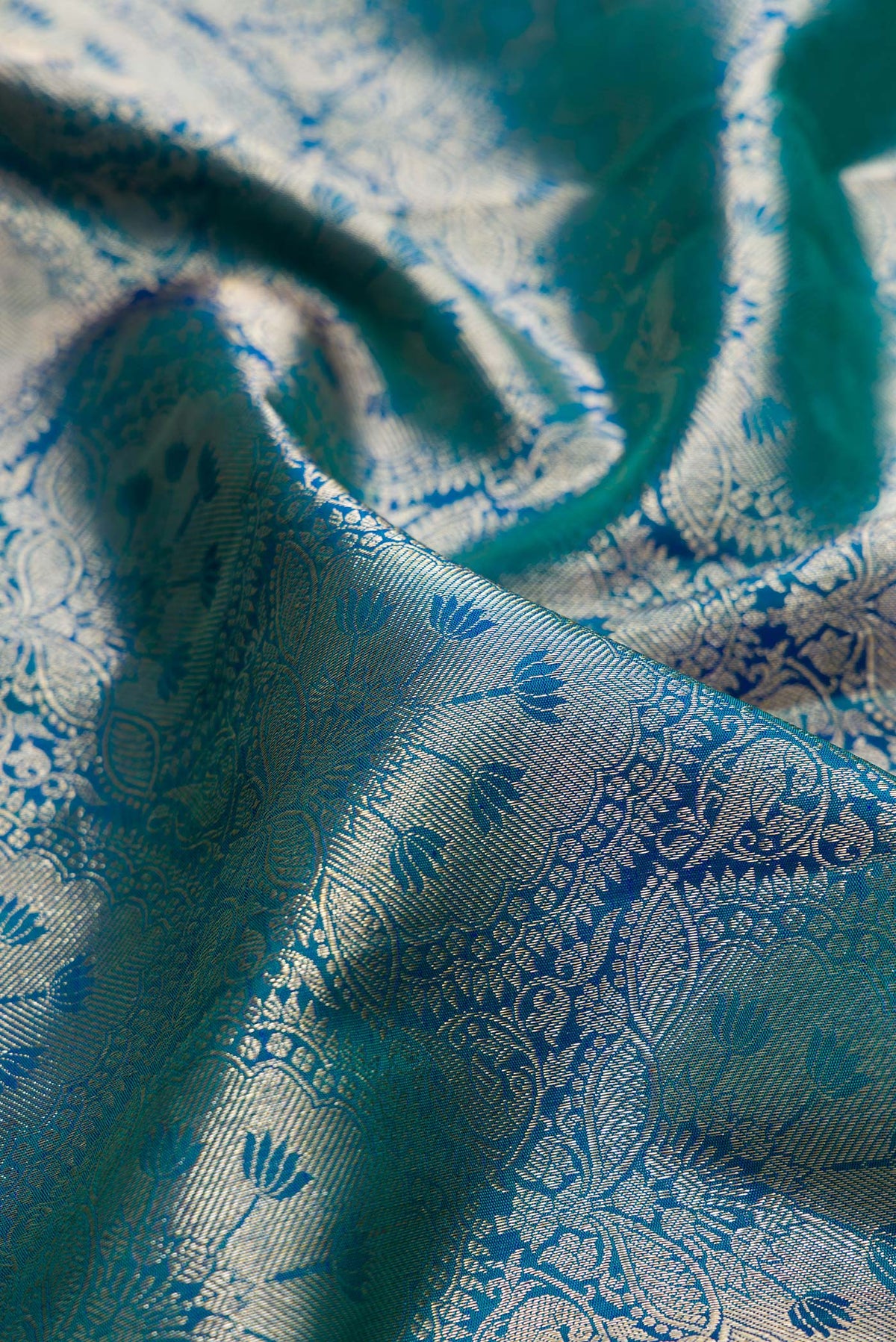 Close up of Pure Silk Peacock Blue Dual Tone Kanchipuram Saree with Zari Brocade on the body and Zari Border.  displaying folds
