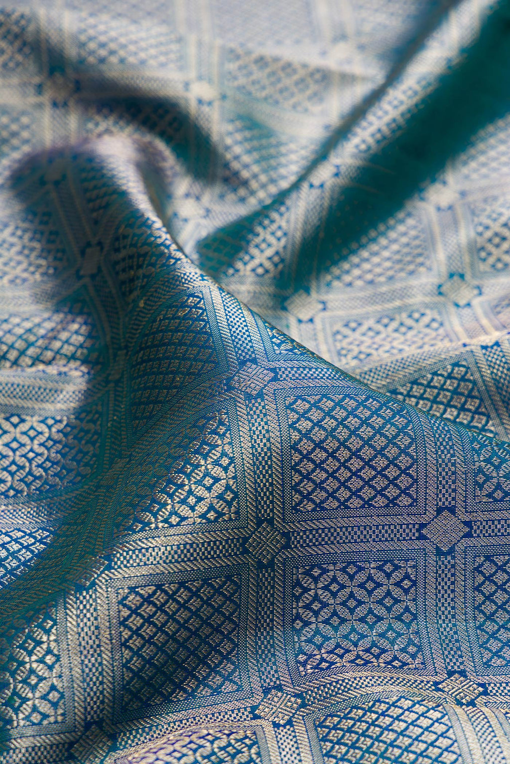 Close up of Pure Silk Peacock Blue Dual Tone Kanchipuram Saree with Zari Brocade on the body and Fancy Border.  displaying folds