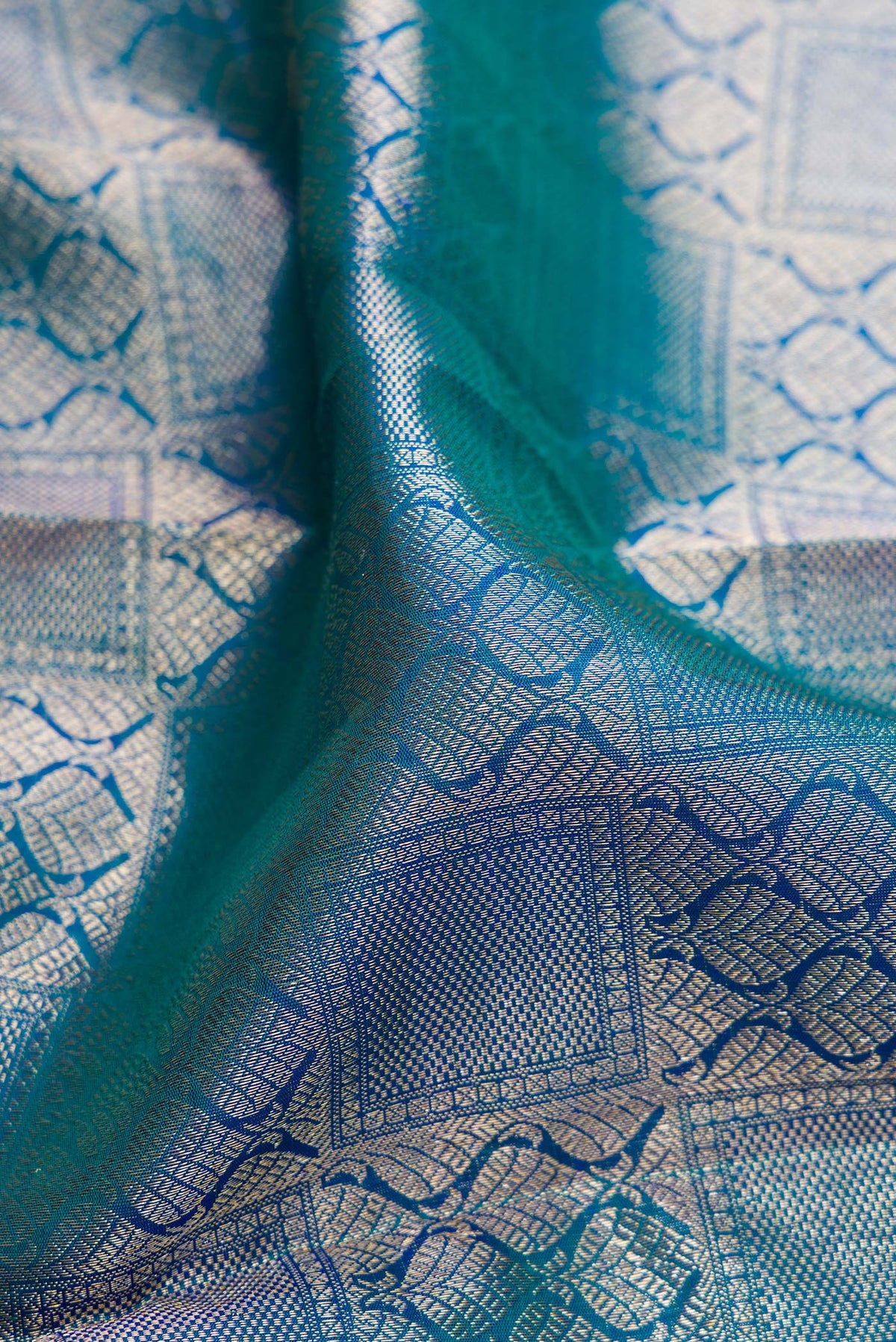 Close up of Pure Silk Peacock Blue Dual Tone Kanchipuram Saree with Zari Brocade on the body and Zari Border.  displaying folds