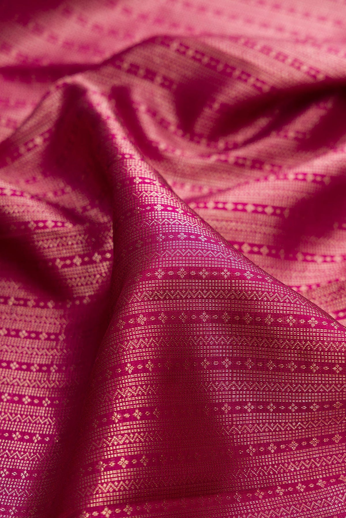 Close up of Pure Silk Dark Pink Kanchipuram Saree with Zari Brocade on the body and Zari Border.  displaying folds