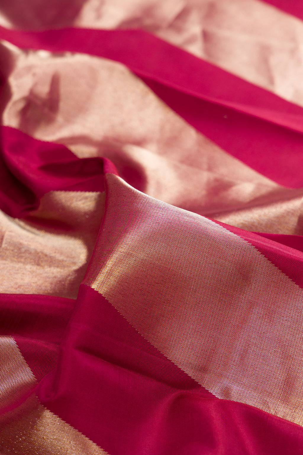 Close up of Pure Silk Maroon Kanchipuram Saree with Zari Butta on the body and Zari Border.  displaying folds