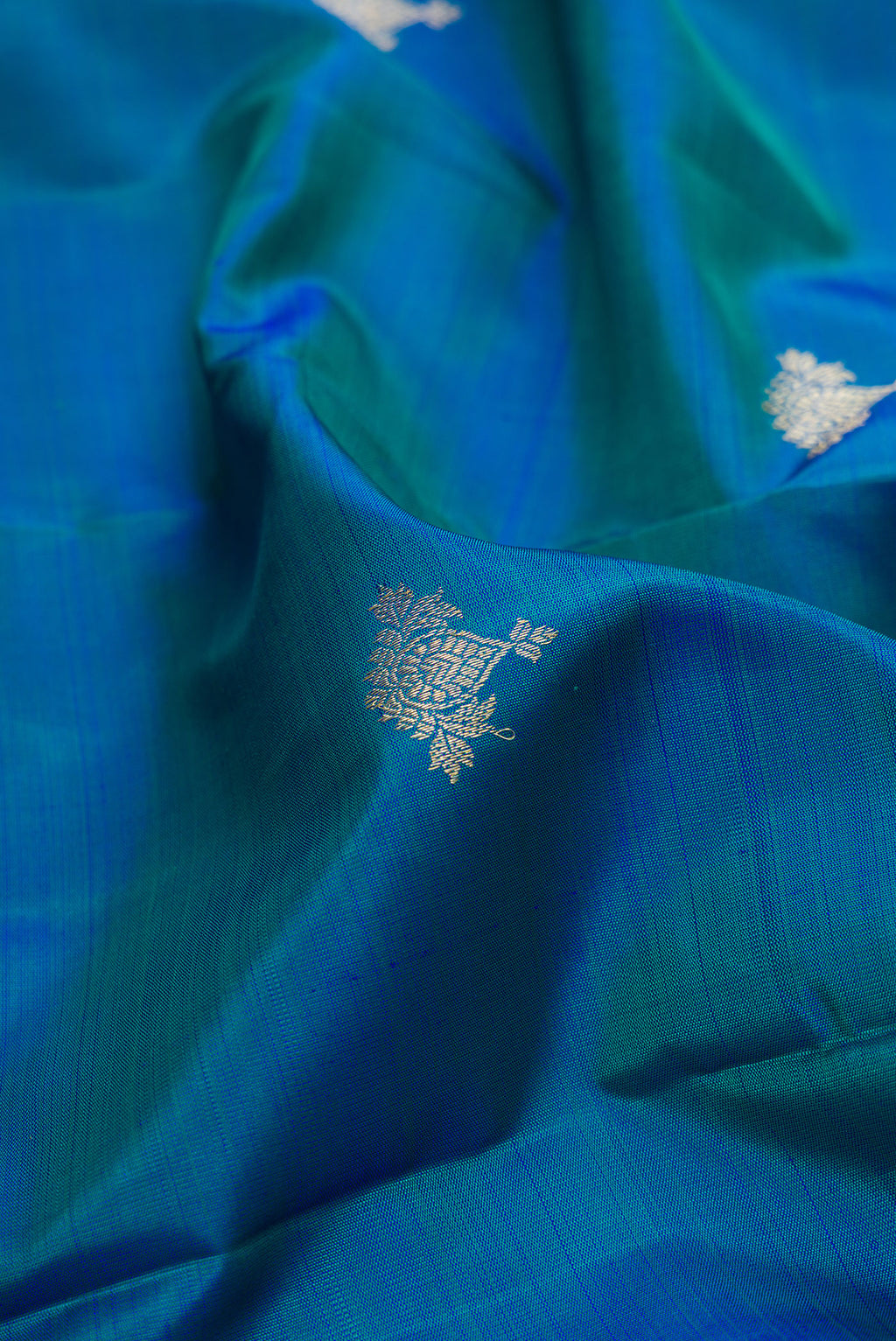 Close up of Pure Silk Peacock Blue Dual Tone Kanjivaram Saree with Zari Butta on the body and Fancy Border.  displaying folds