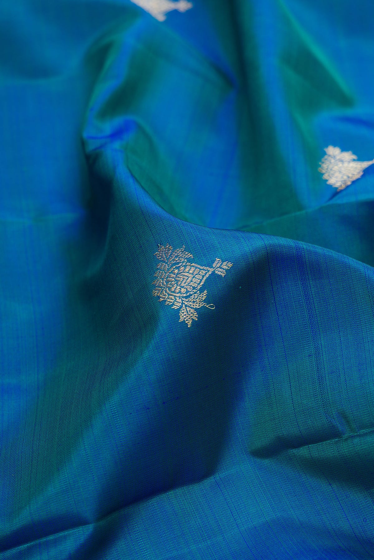 Close up of Pure Silk Peacock Blue Dual Tone Kanjivaram Saree with Zari Butta on the body and Fancy Border.  displaying folds