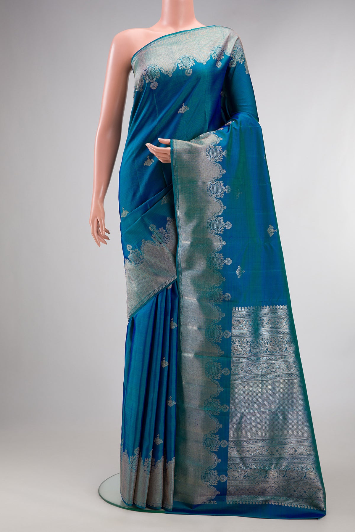 Pure Silk Peacock Blue Dual Tone Kanjivaram Saree with Zari Butta on the body and Fancy Border.  displayed on a mannequin