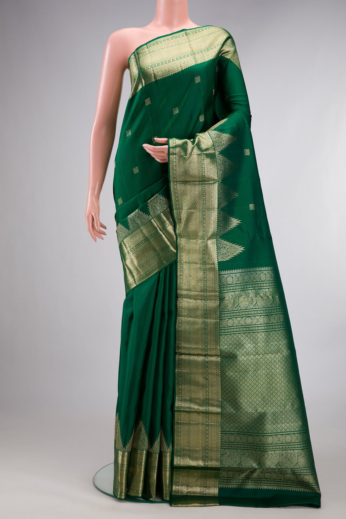 Pure Silk Green Kanjivaram Saree with Zari Butta on the body and Temple Border.  displayed on a mannequin