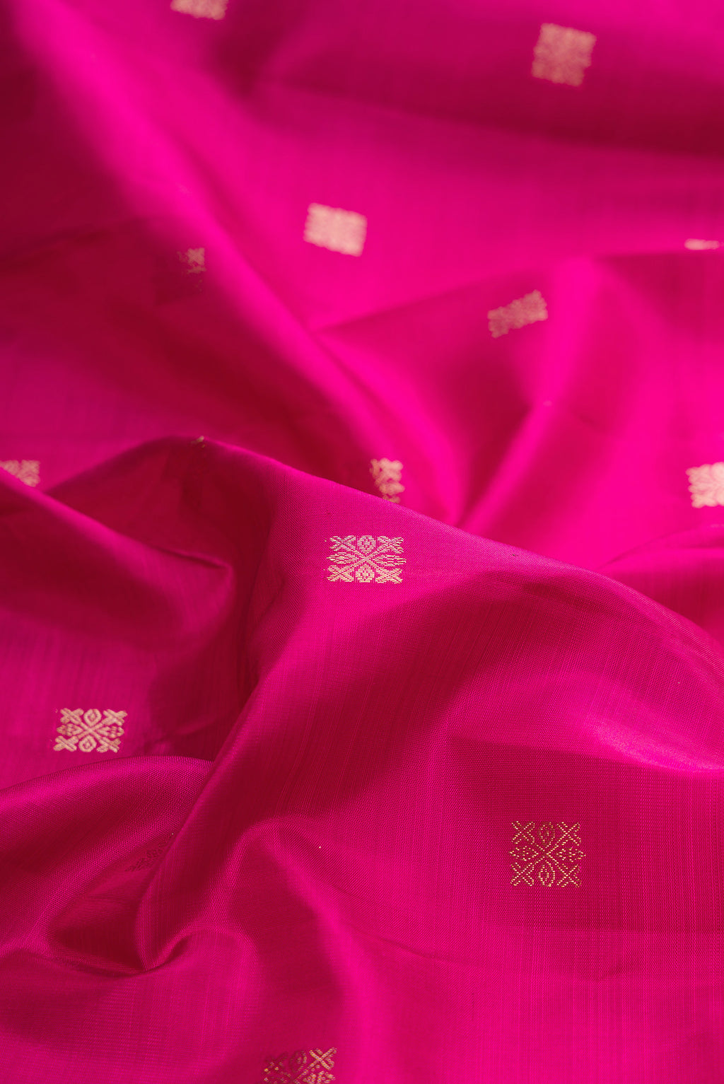 Close up of Pure Silk Rani Pink Kanjivaram Saree with Zari Butta on the body and Zari Border.  displaying folds