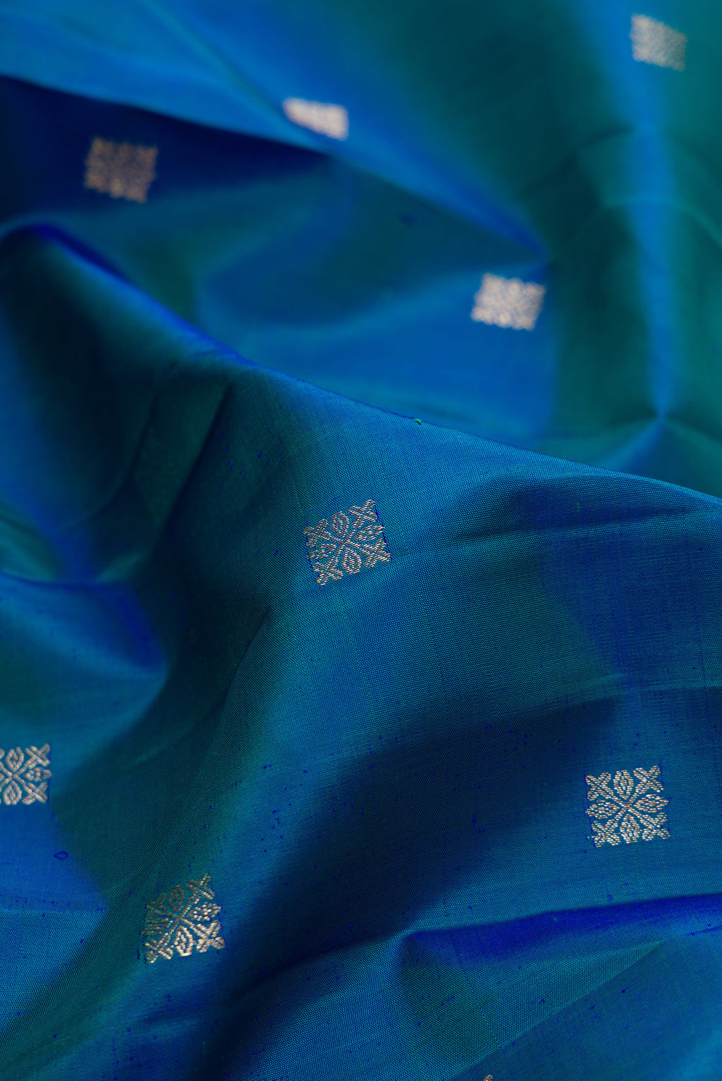 Close up of Pure Silk Peacock Blue Dual Tone Kanjivaram Saree with Zari Butta on the body and Fancy Border.  displaying folds